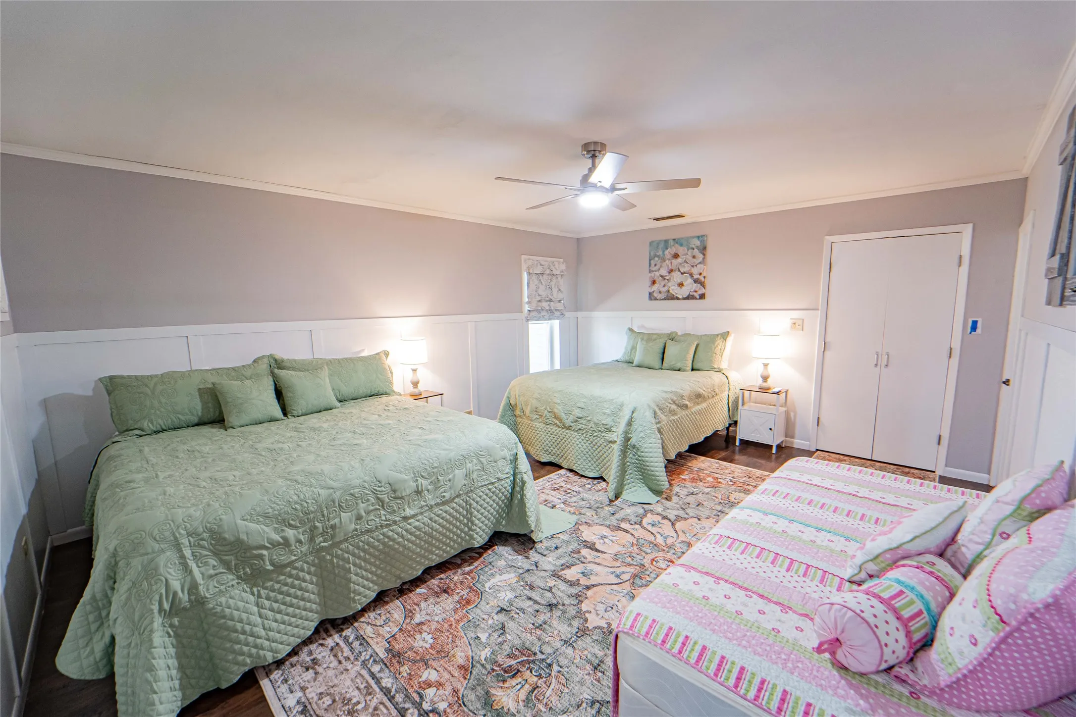 primary-Spacious room with wood-finish flooring, white wainscoting, and a ceiling fan with integrated lighting
