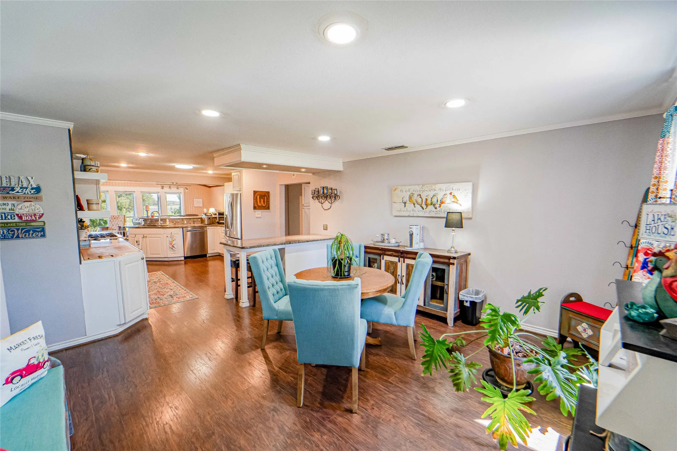 Open-concept dining area featuring granite topped breakfast bar, wood-finish flooring, recessed lighting, and a white kitchen with stainless steel appliances