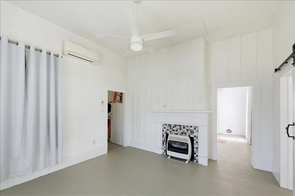 Bright living area displaying white panel walls, a decorative fireplace mantle, and neutral flooring.