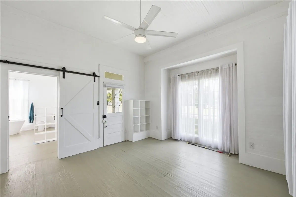 Spacious open interior room featuring sliding white barn doors, high ceilings, and bright natural light.