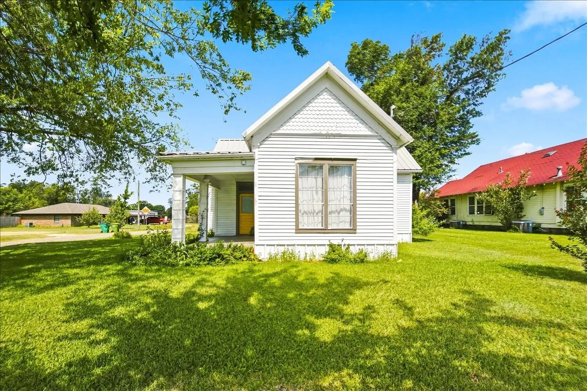 Front view of the white home showcasing its classic architectural details and well-kept front yard.