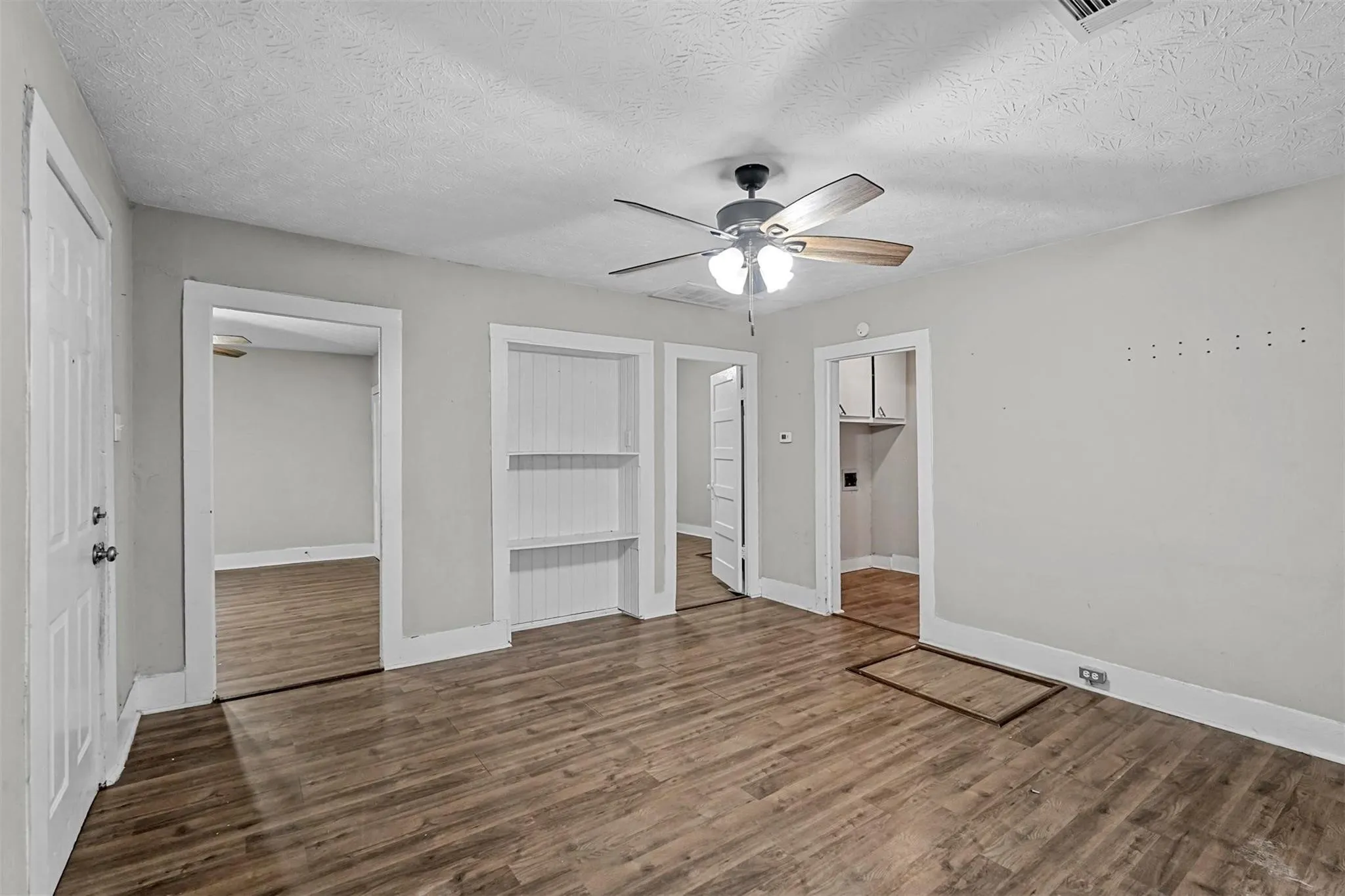 Unfurnished bedroom featuring a closet, wood finished floors, a textured ceiling, and ceiling fan