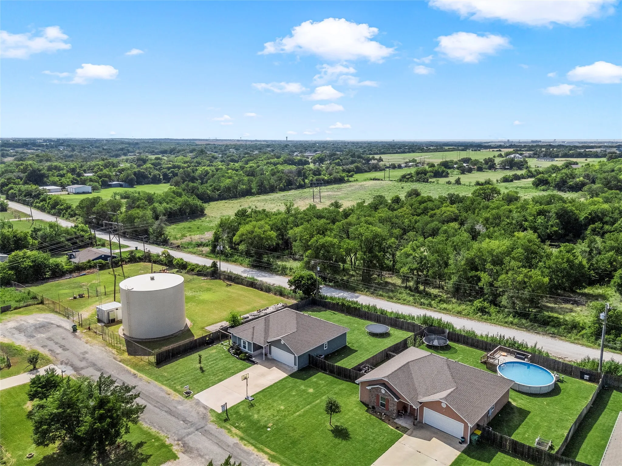 Aerial perspective showcasing two residential properties with expansive green surroundings