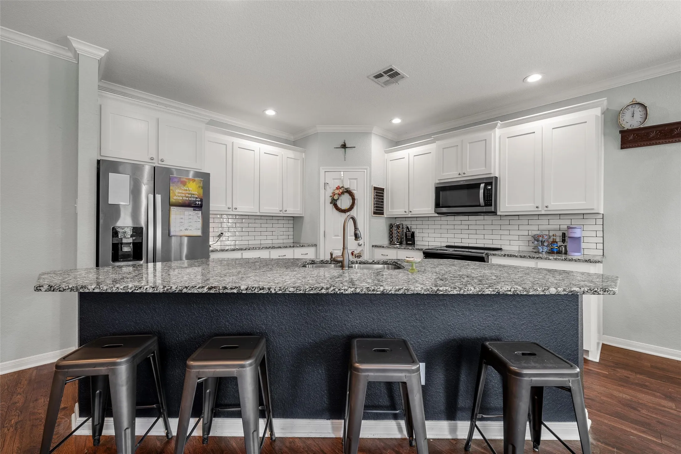 Kitchen featuring a large island with a durable countertop, white shaker cabinetry, stainless steel appliances, a subway tile backsplash, and recessed lighting