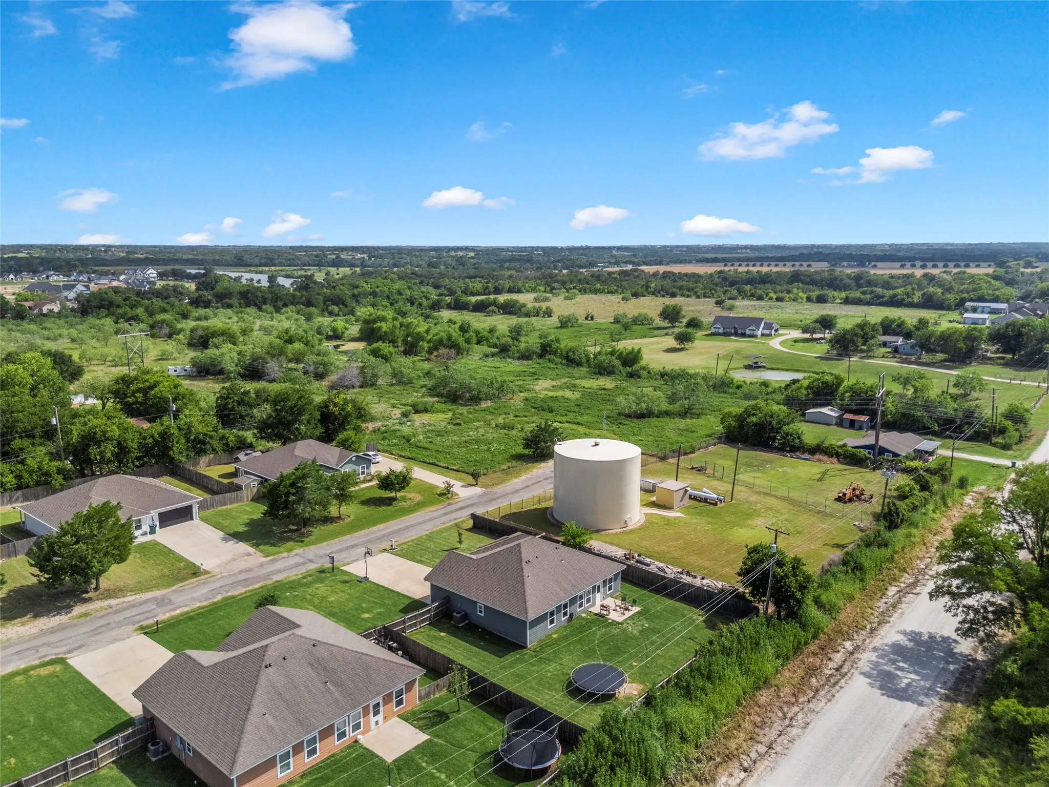 Expansive rural landscape featuring scattered residential properties, mature trees, and open fields under a clear sky