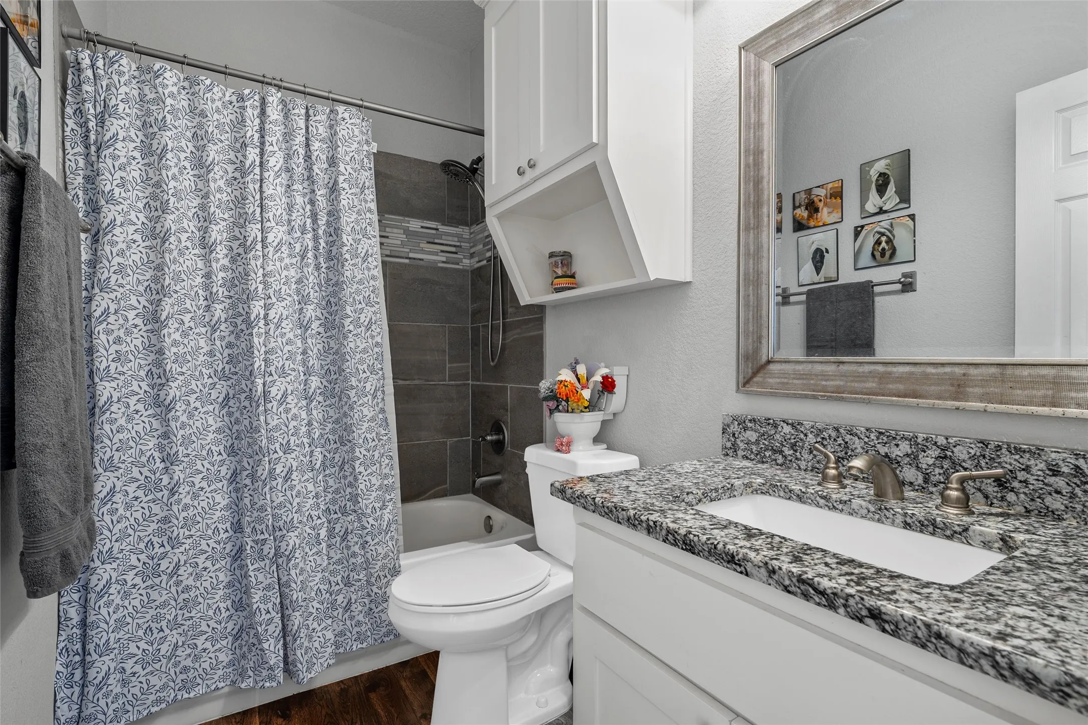 Bathroom featuring a white vanity with a dark speckled countertop, an undermount sink, and a framed mirror