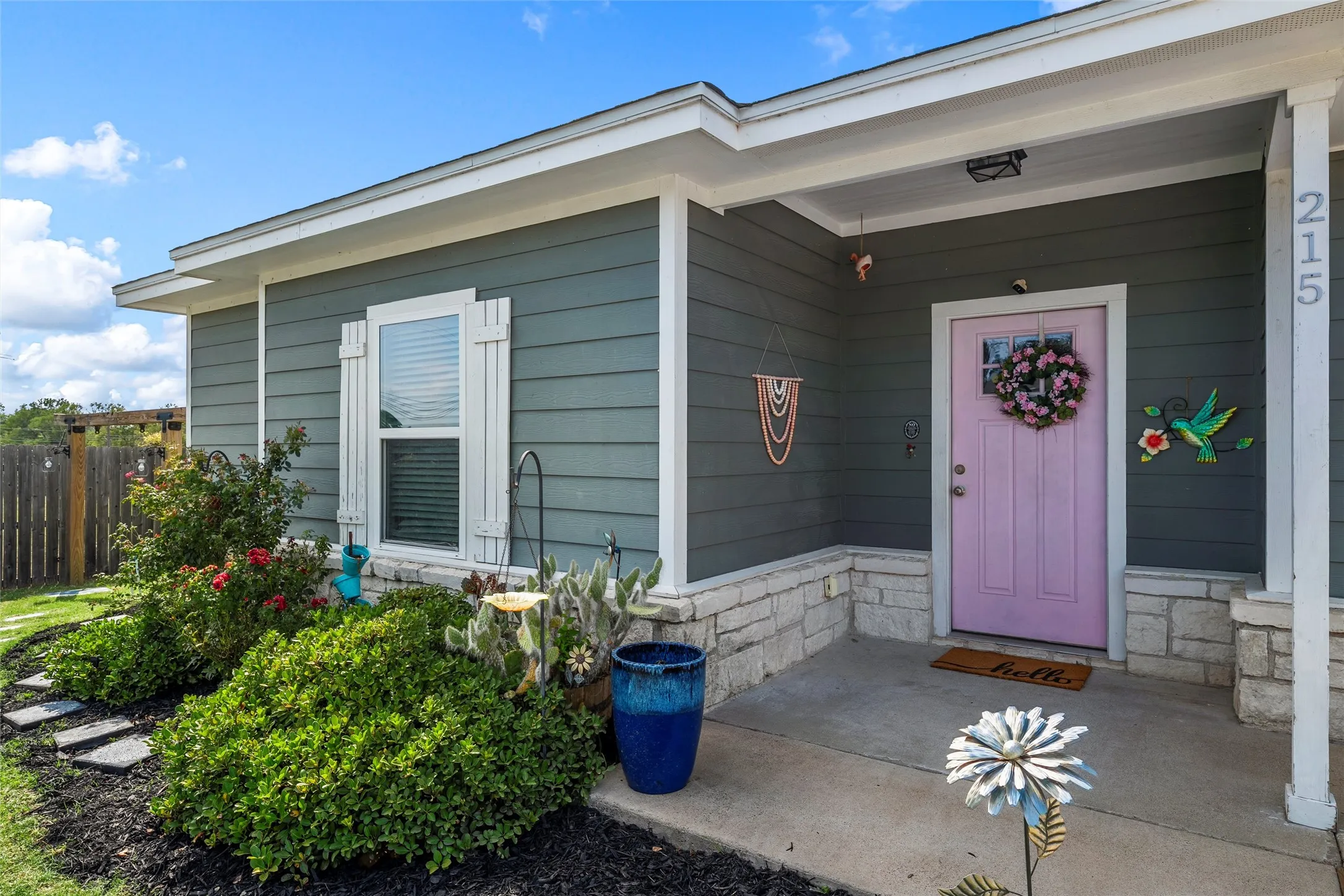 Front entry featuring a lavender door, gray siding, and a stone facade