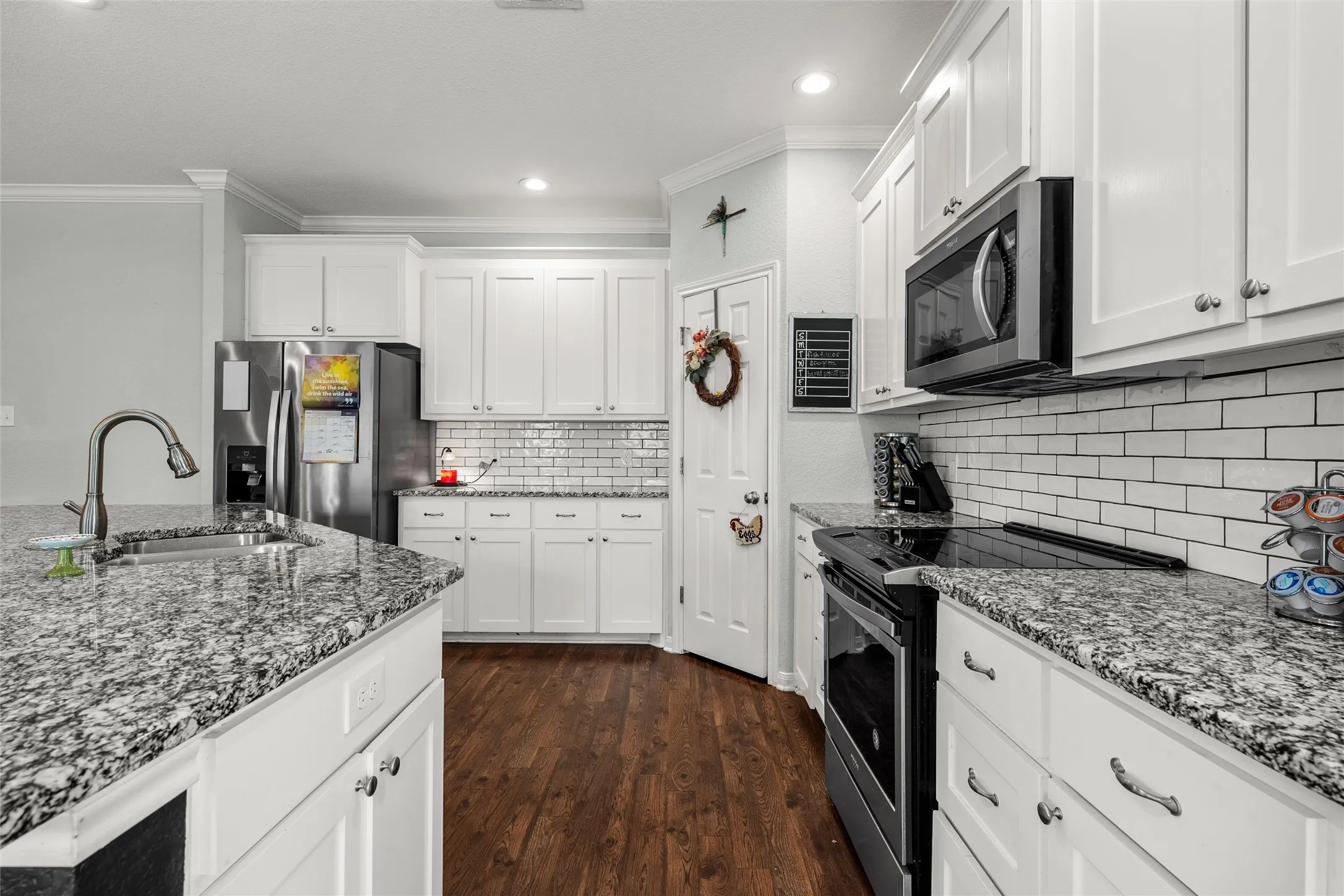 Bright kitchen featuring white cabinetry, granite countertops, and wood-finish flooring
