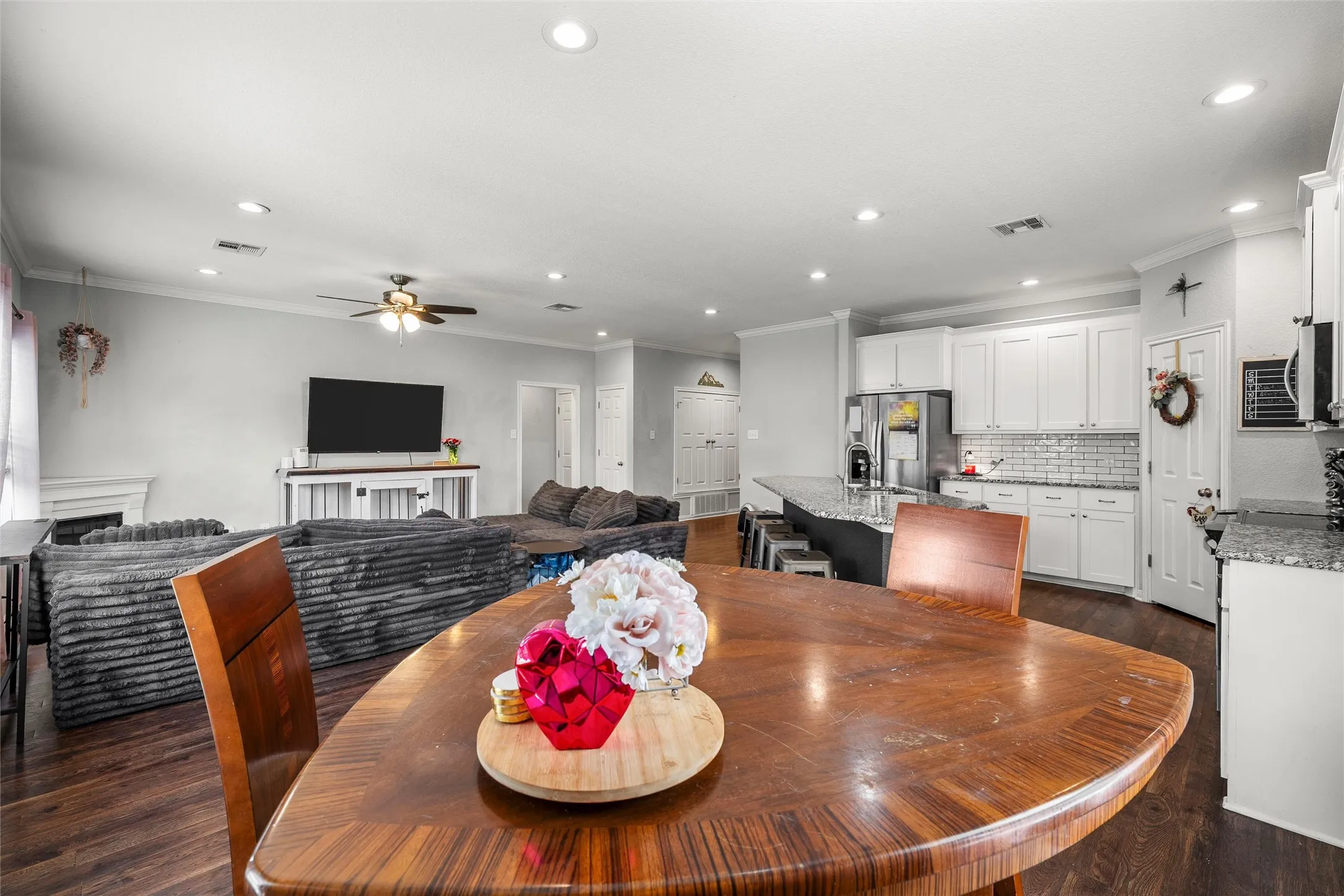 Open-concept living space featuring wood-finish flooring, recessed lighting, and crown molding