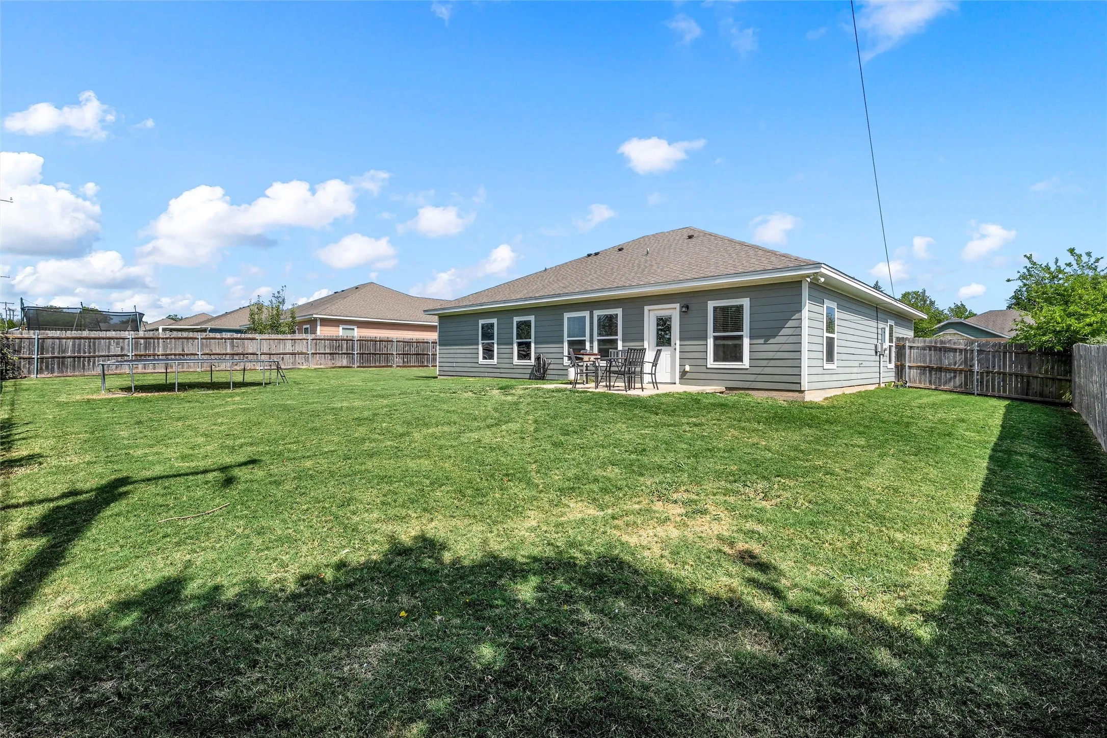 Expansive backyard featuring a lush lawn and a wood privacy fence