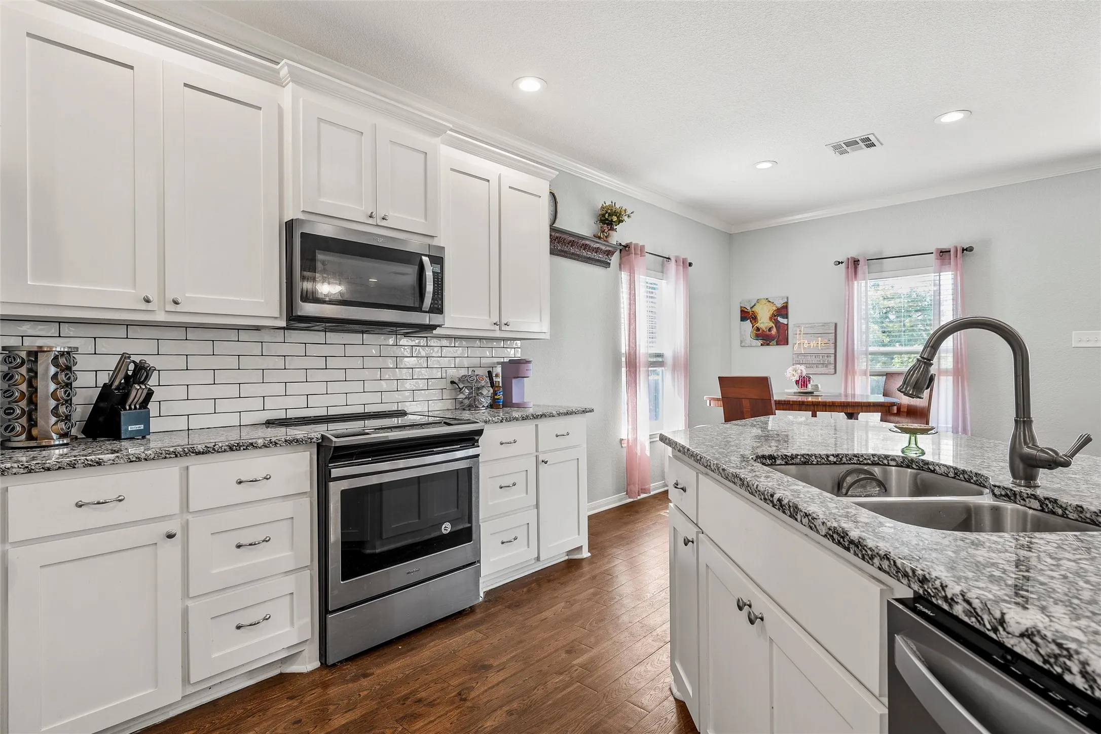 Modern kitchen featuring white cabinetry, granite countertops, and wood-finish flooring