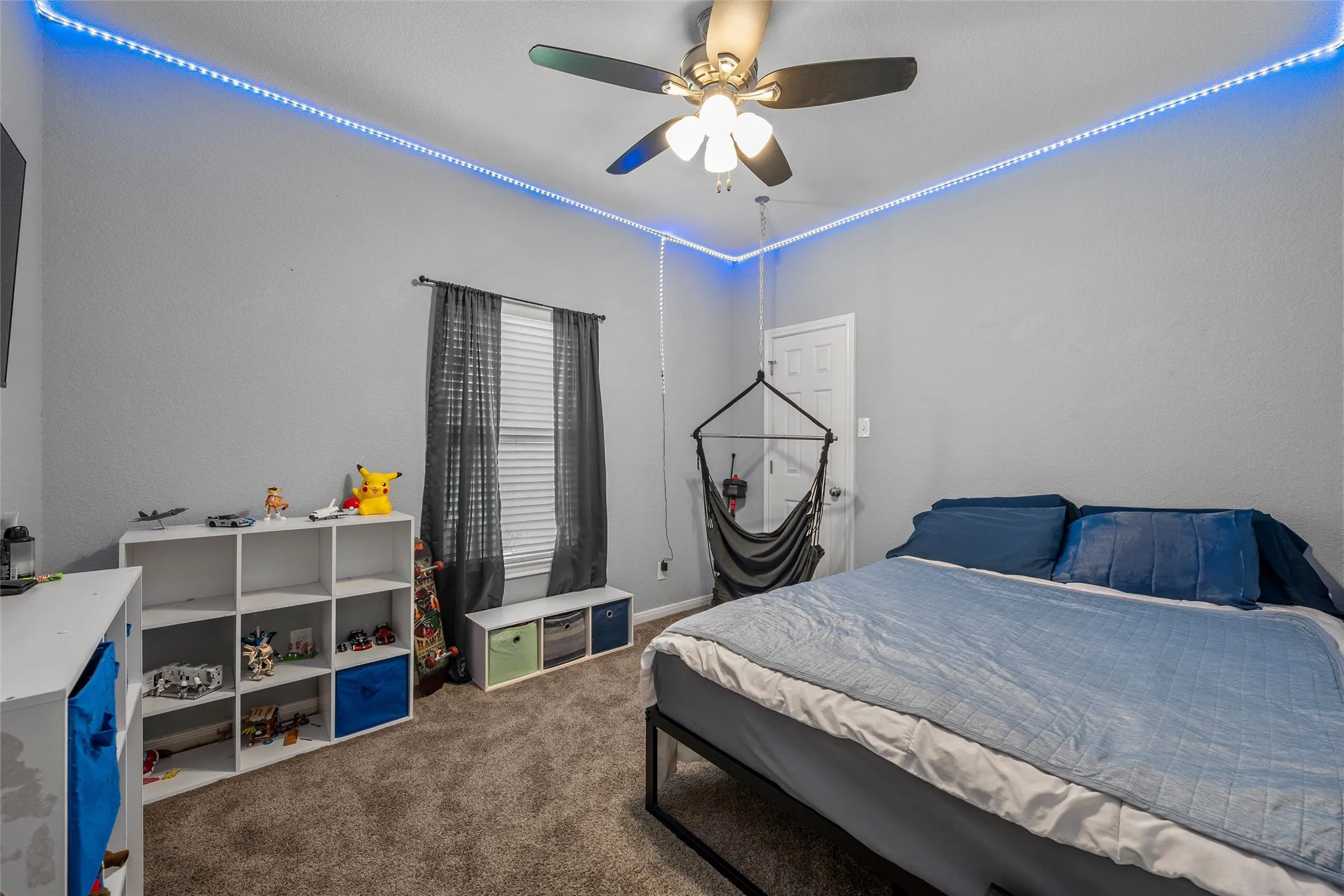 Carpeted room with a ceiling fan light fixture, overhead accent lighting, and a window with blinds