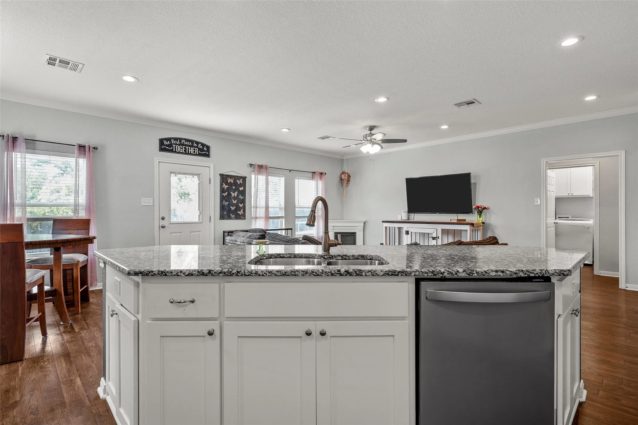 Kitchen island featuring a granite countertop, undermount sink, and integrated dishwasher
