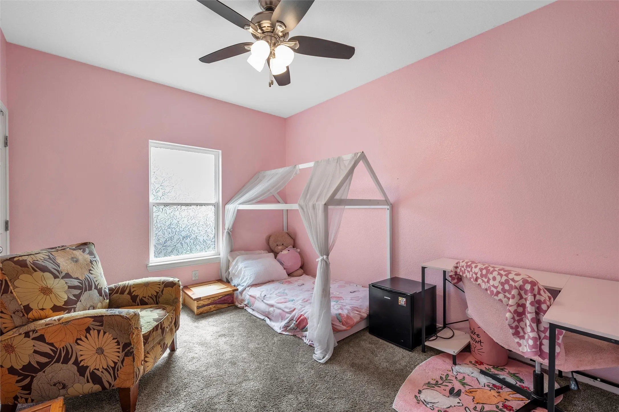 Bedroom featuring a ceiling fan with integrated lighting, frosted window, and soft carpet flooring