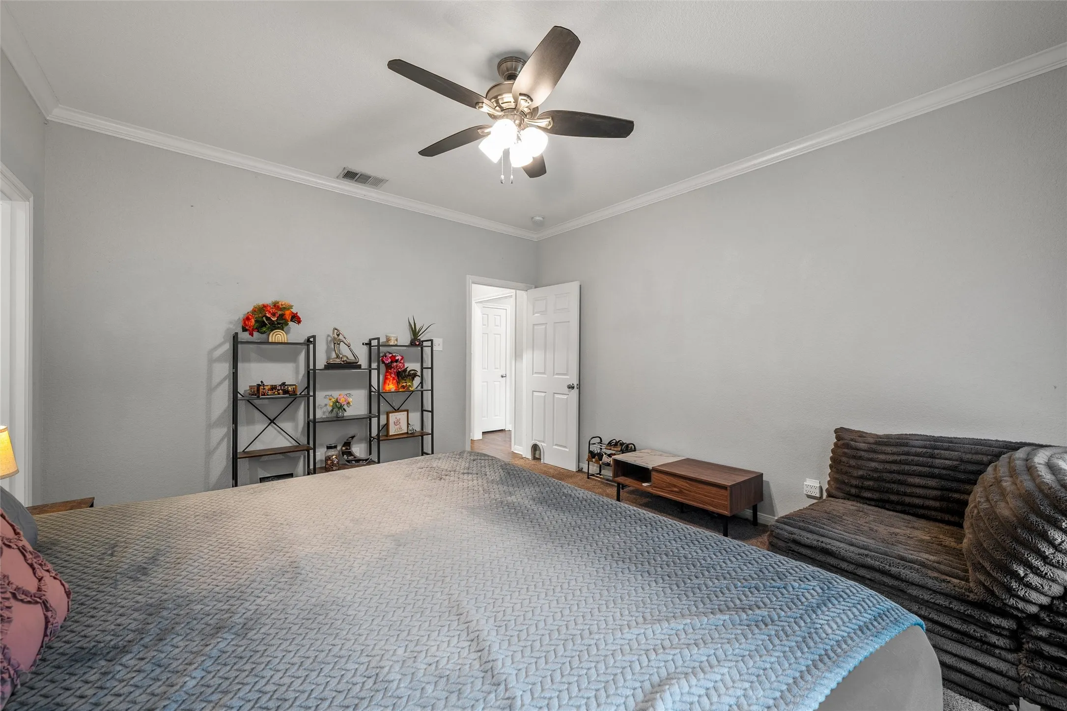 Spacious interior featuring a ceiling fan, white crown molding, wood-finish flooring, and light gray wall paint