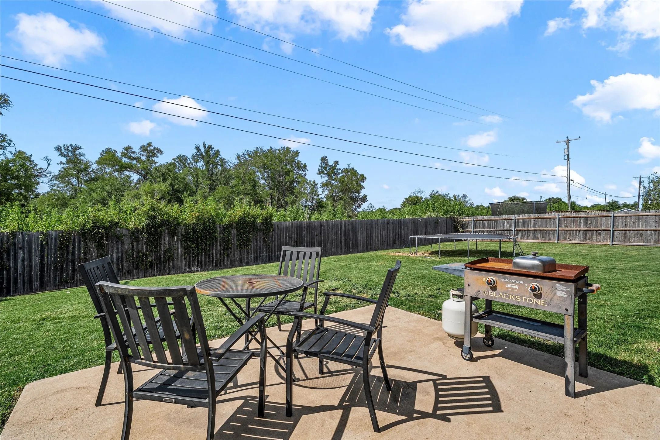 Expansive backyard featuring a concrete patio, grassy lawn, and wood privacy fencing