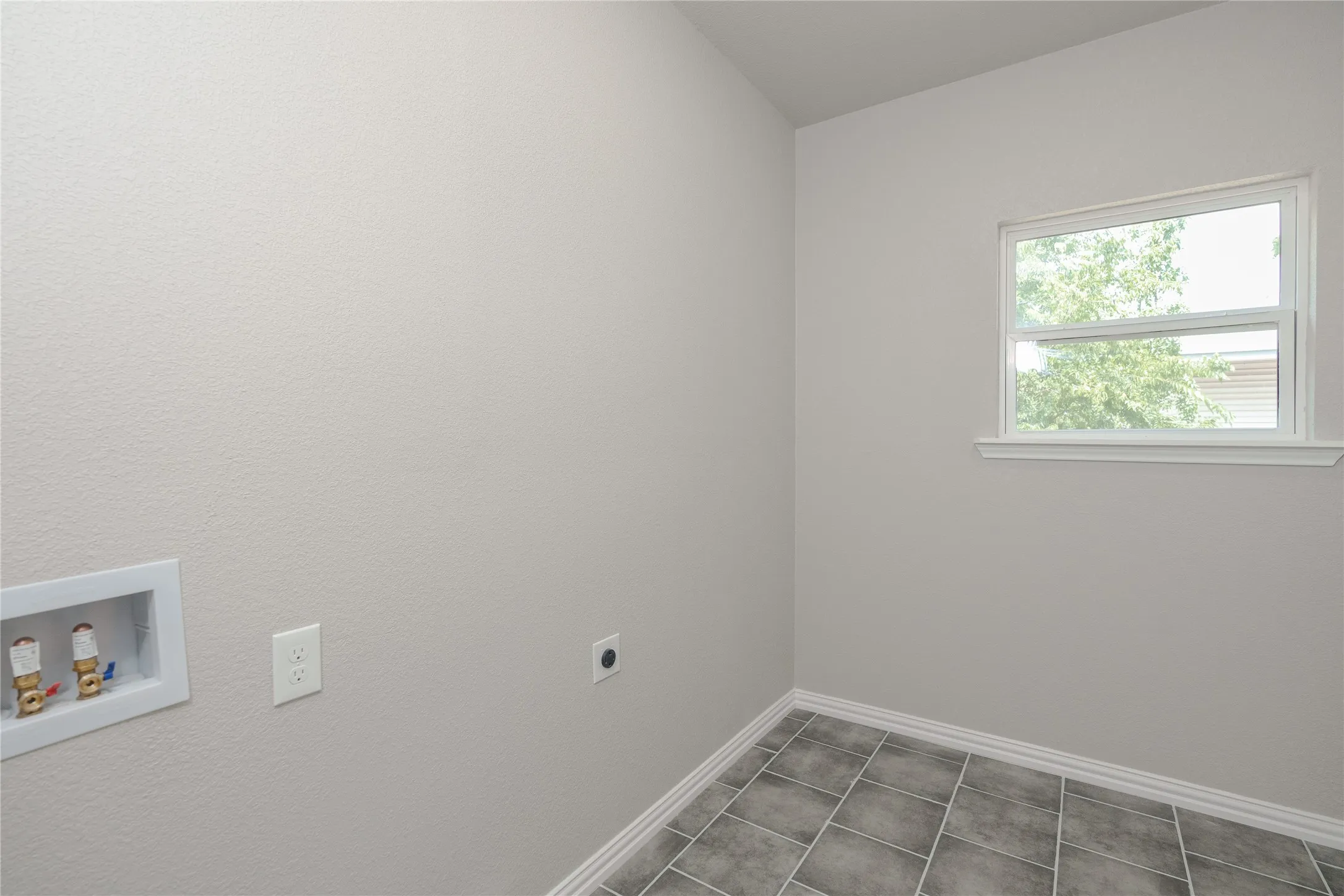Utility room featuring a window, tile flooring, and light-colored walls