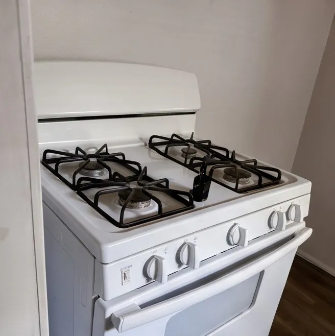 White freestanding range with a four-burner gas cooktop and an integrated oven