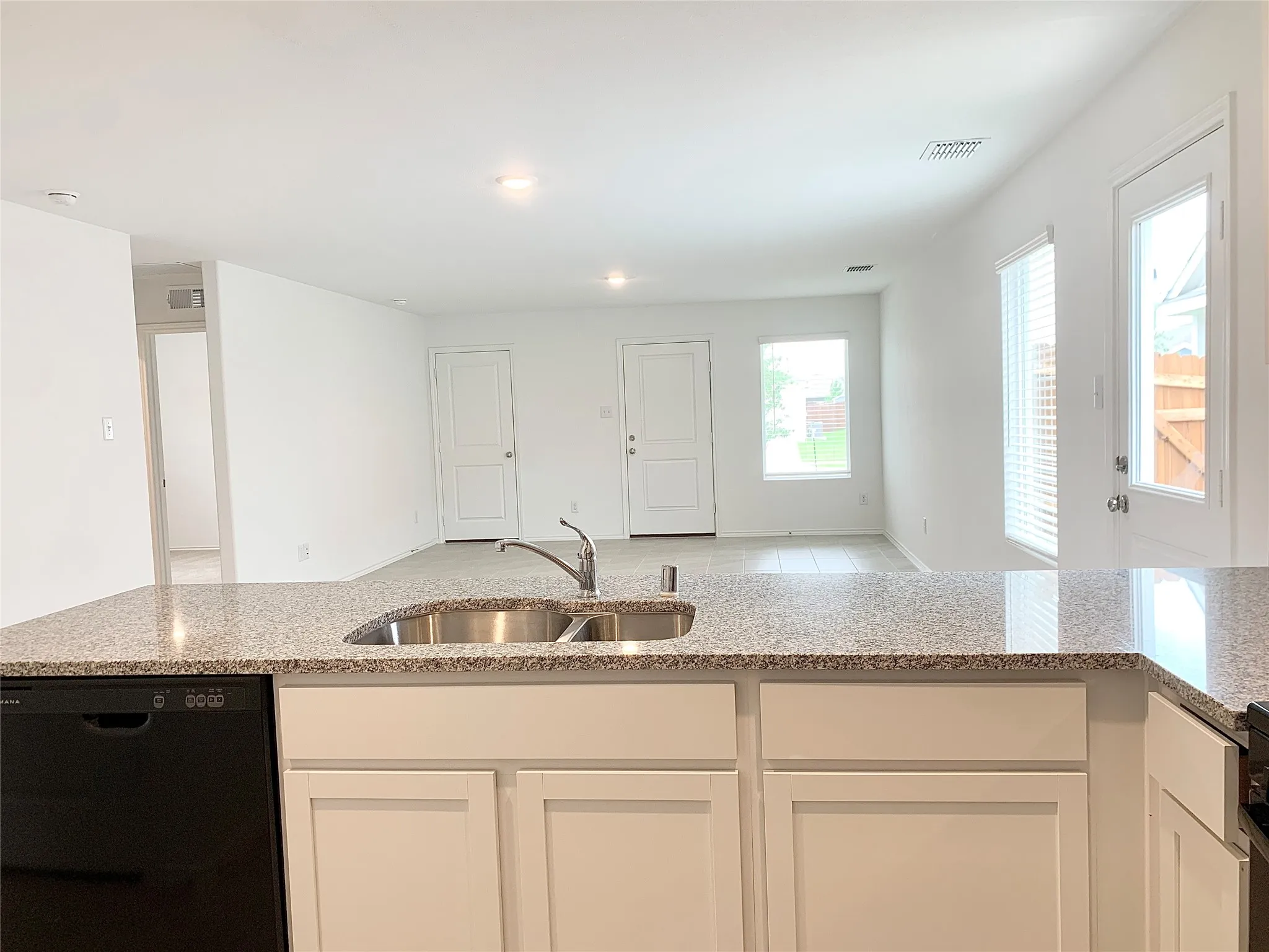 Kitchen with sink, light stone countertops, dishwasher, and white cabinetry