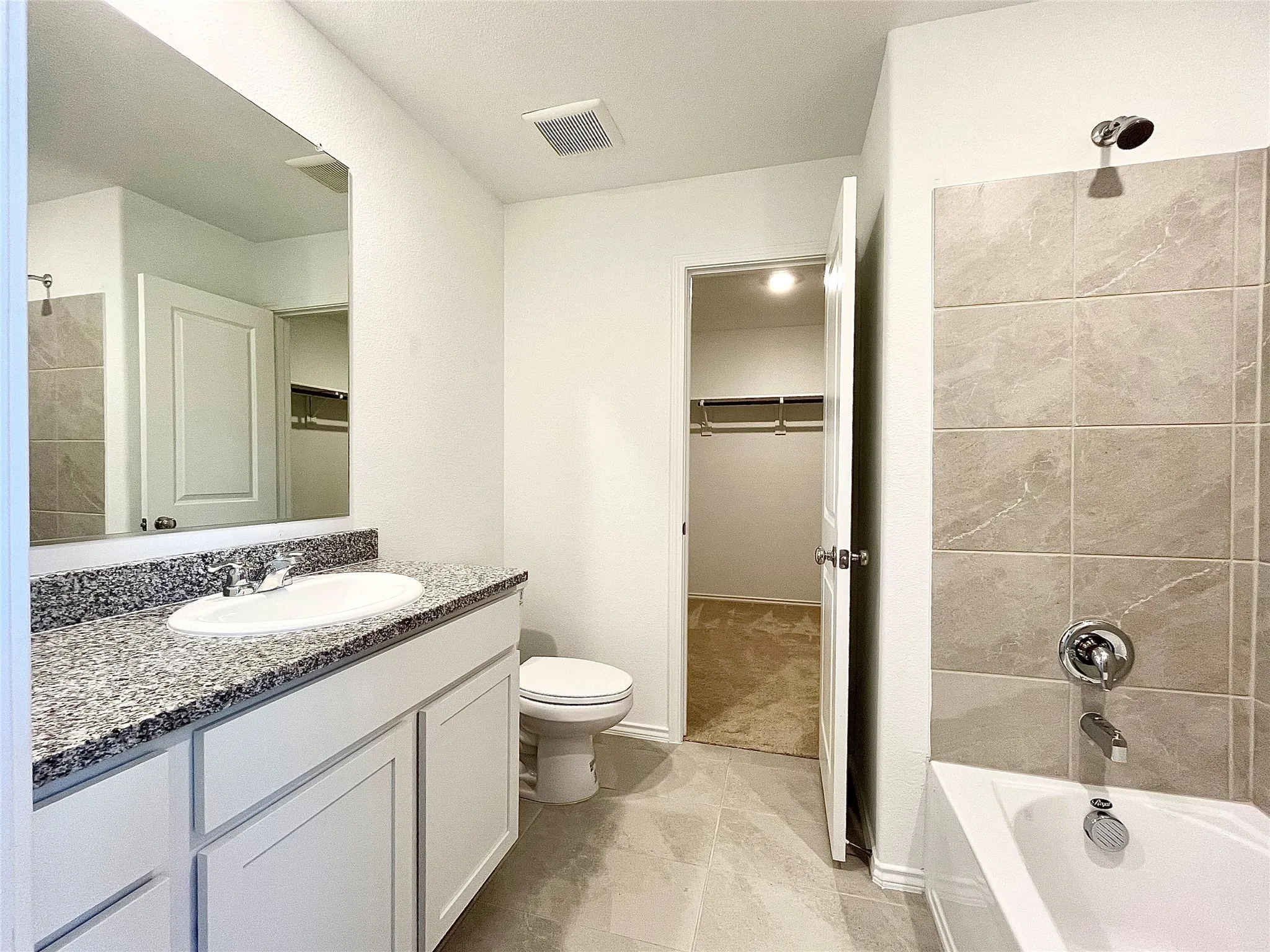 Bathroom with vanity, bathing tub / shower combination, and a spacious closet