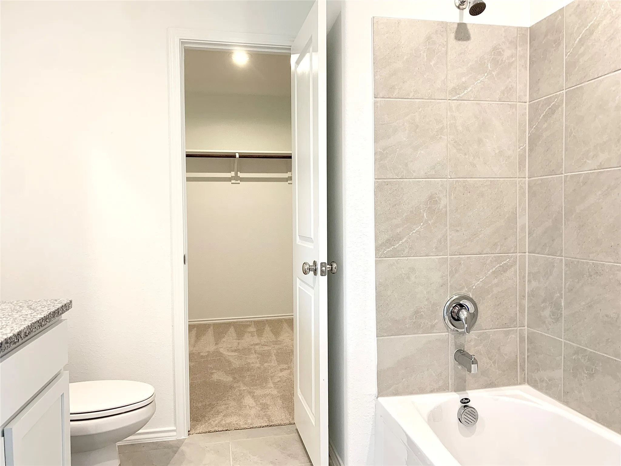 Full bathroom featuring tile flooring, vanity, tiled shower / bath combo, and toilet