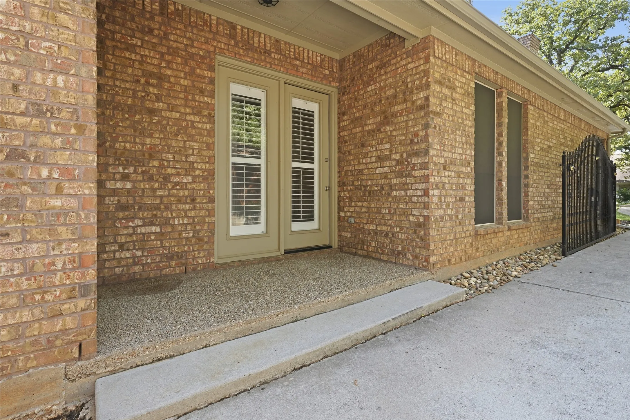 Brick exterior with double glass-panel doors featuring interior plantation shutters