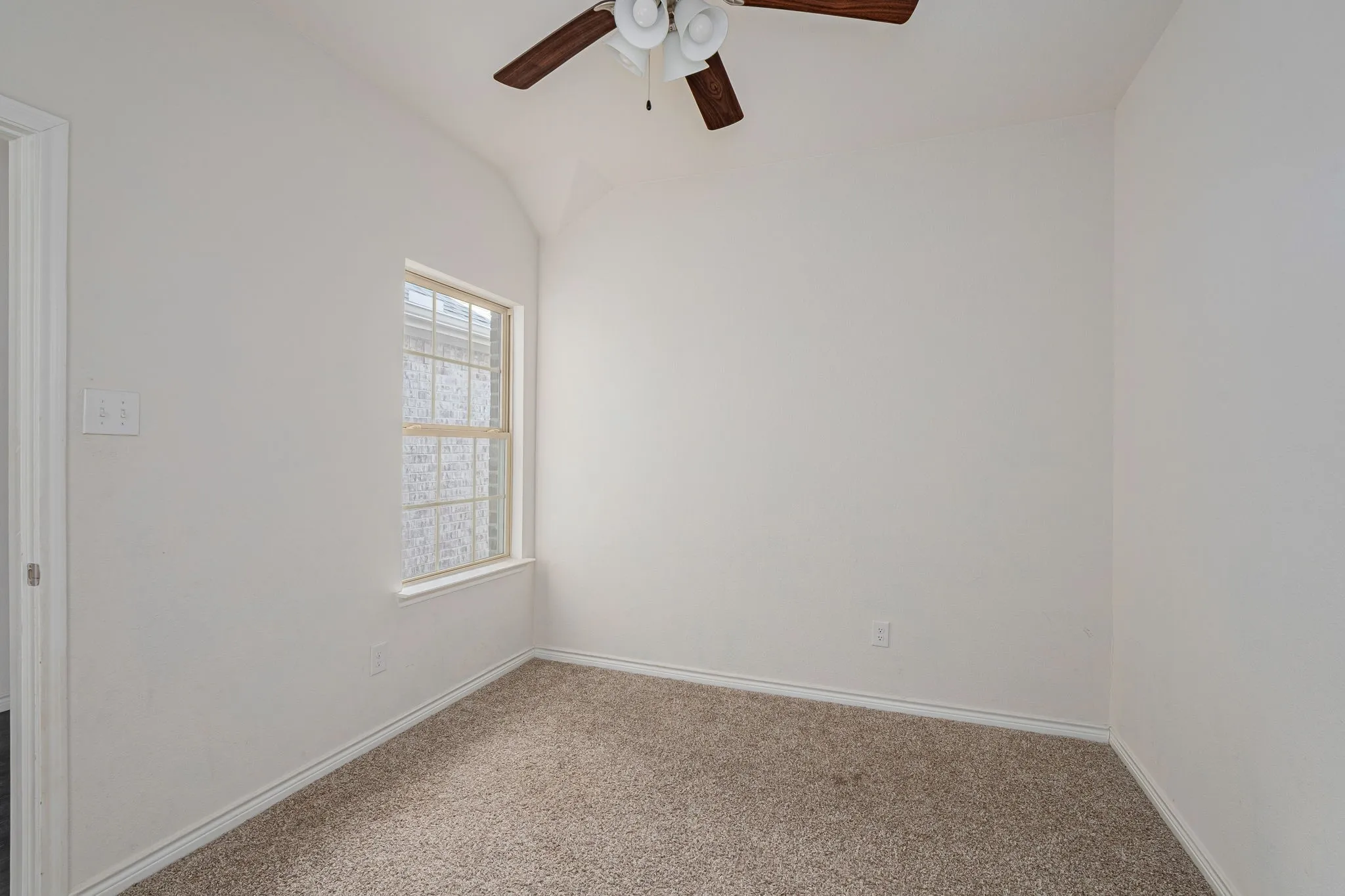 Carpeted empty room featuring a ceiling fan and baseboards