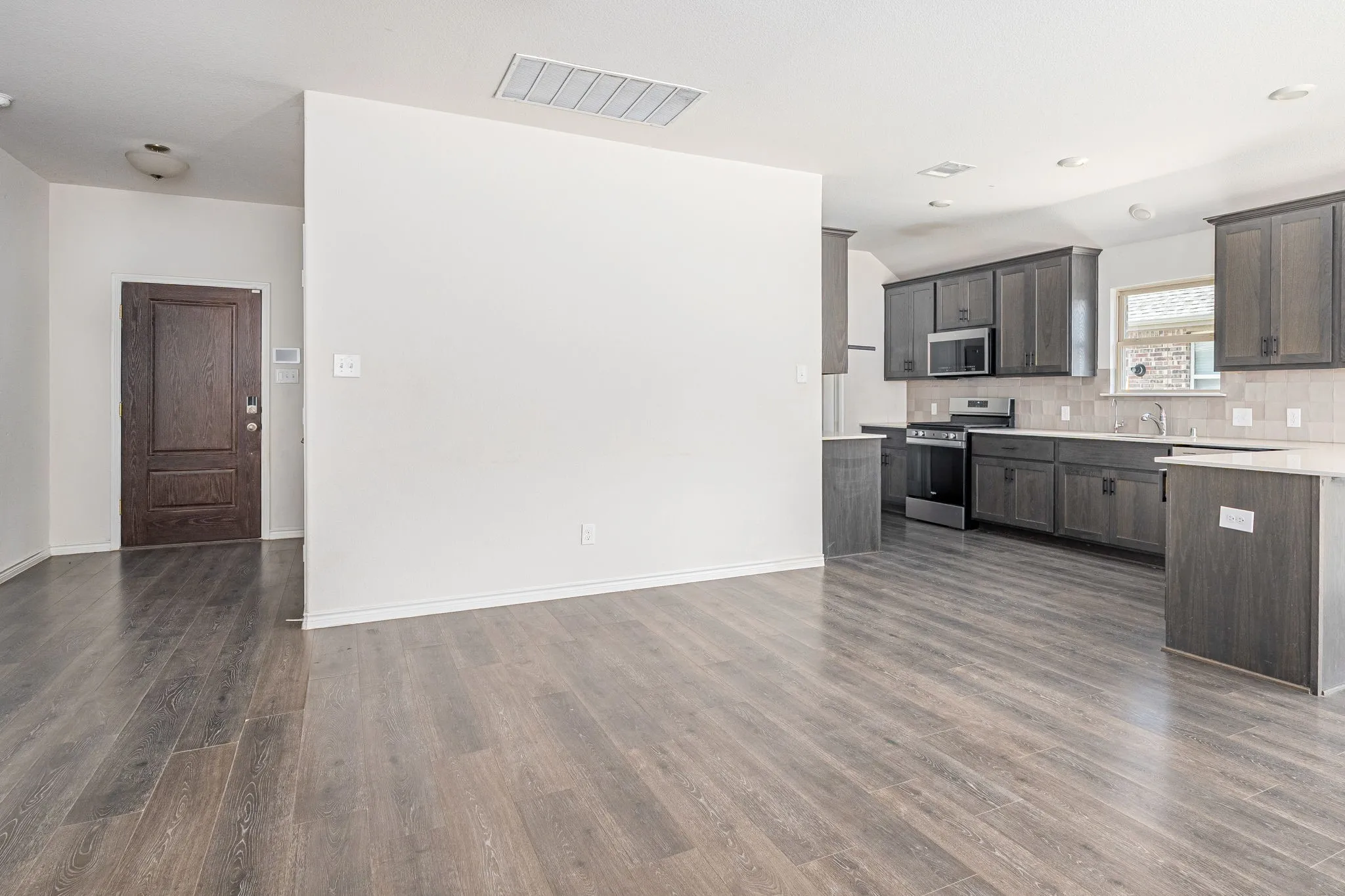 Kitchen featuring stainless steel appliances, backsplash, dark wood-style flooring, dark wood finish cabinetry, and recessed lighting