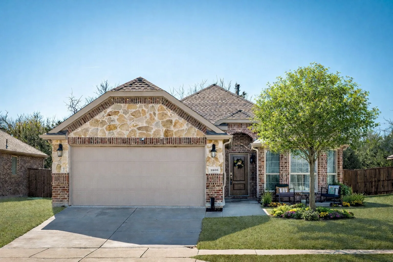 French country inspired facade featuring brick siding, an attached garage, concrete driveway, and stone siding
