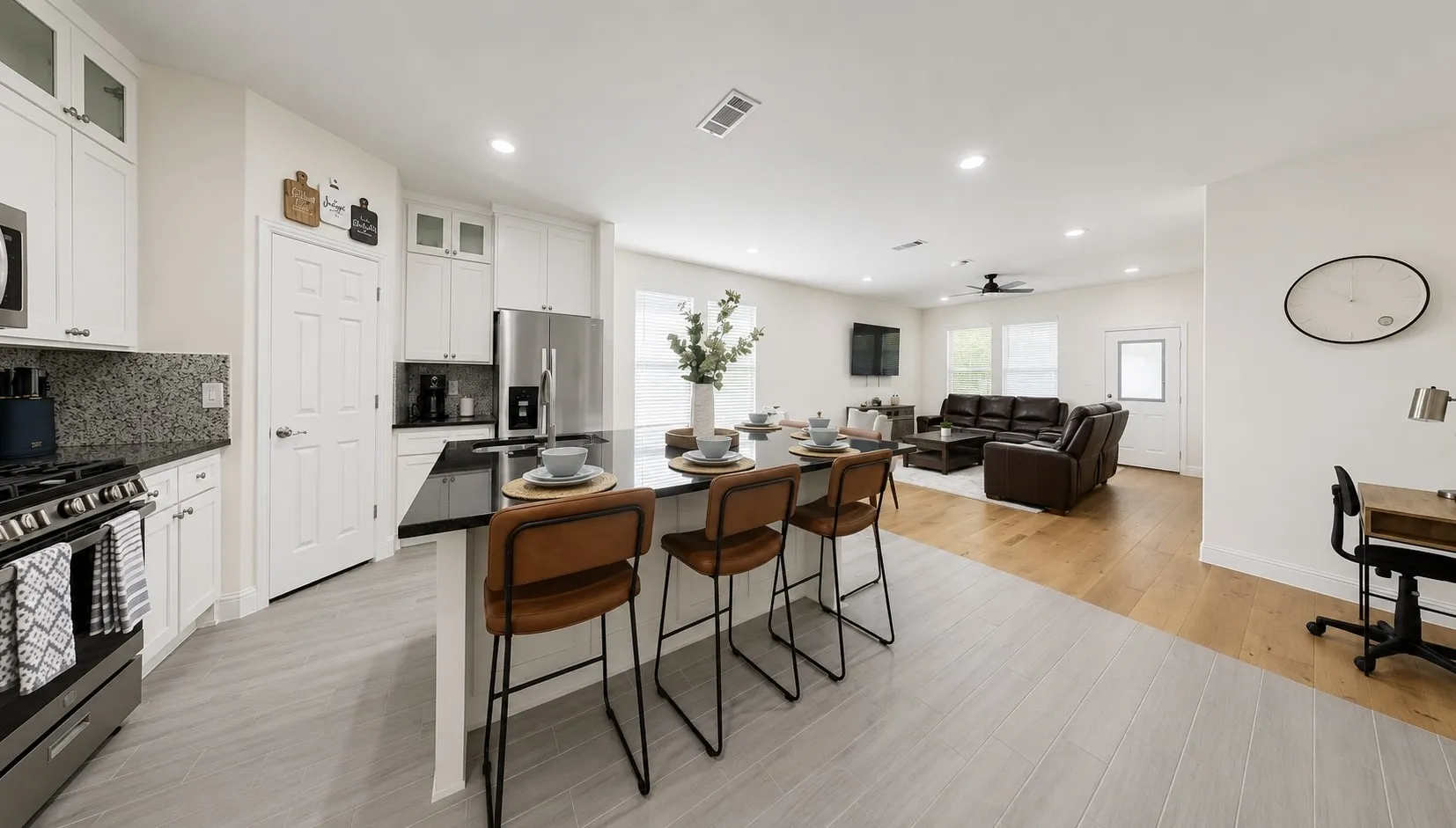 Open-concept living area with a kitchen island, white cabinetry, dark countertops, and stainless steel appliances
