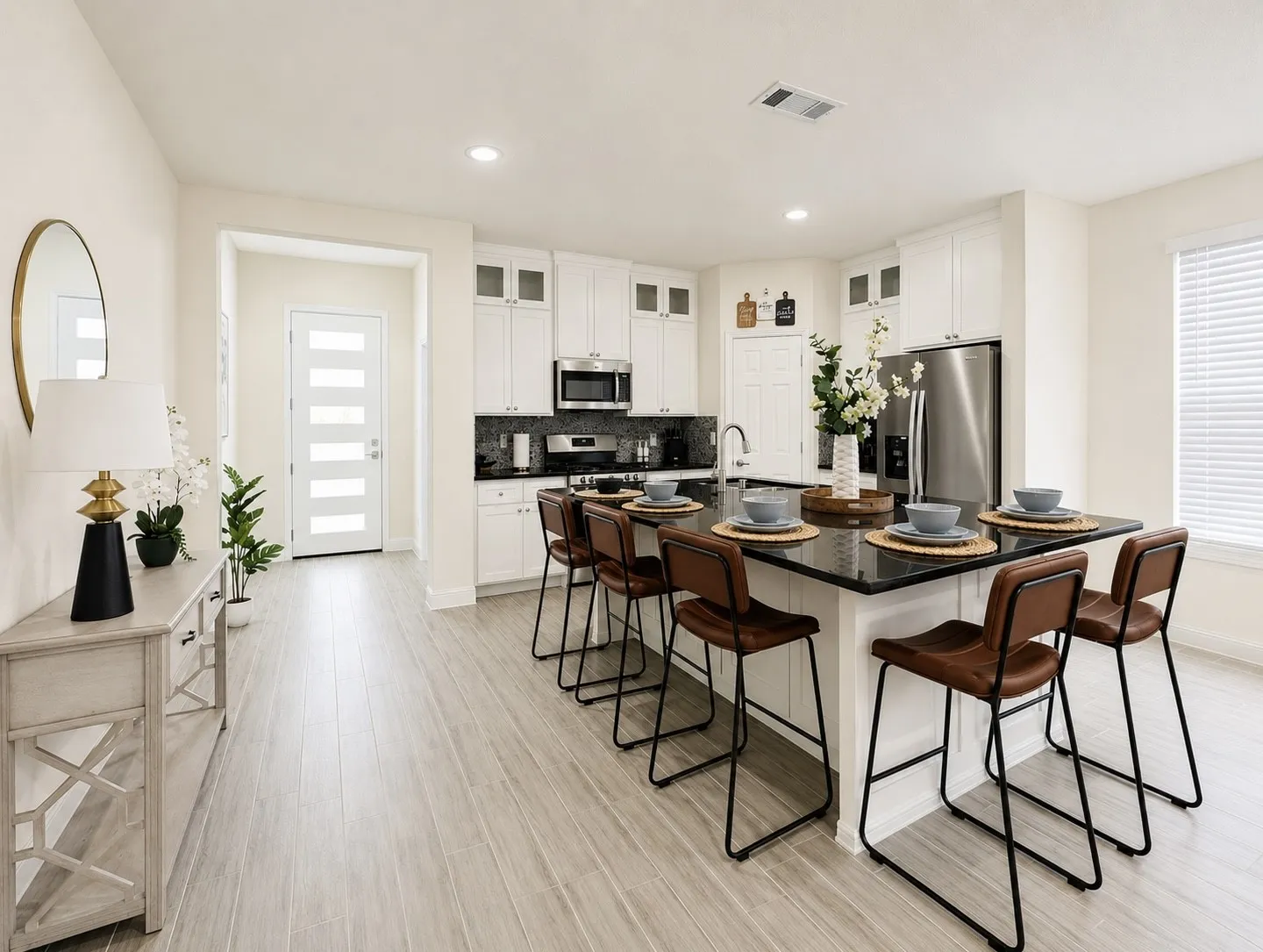 Open-concept kitchen featuring a large island with seating, stainless steel appliances, white cabinetry, dark countertops, and wood-finish flooring
