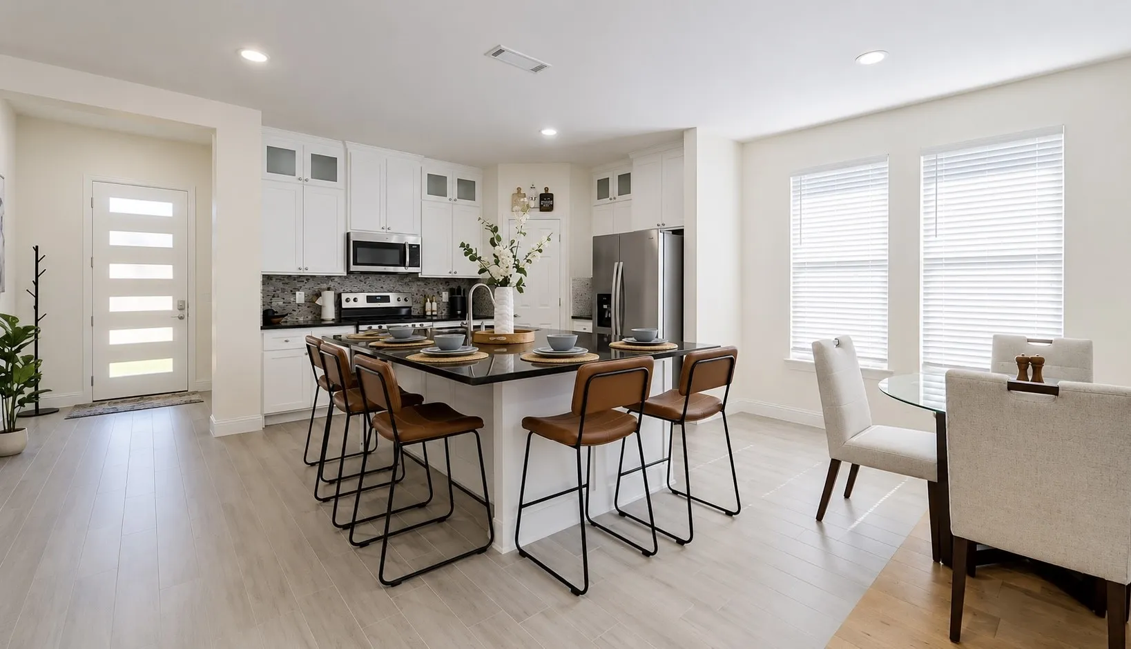 Modern kitchen featuring a large island with a black countertop, white cabinetry with glass-front accents, and stainless steel appliances