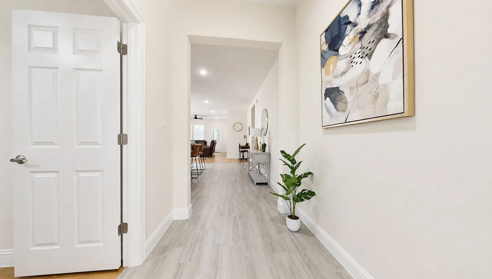 Hallway featuring wood-finish flooring, white baseboards, and a six-panel interior door