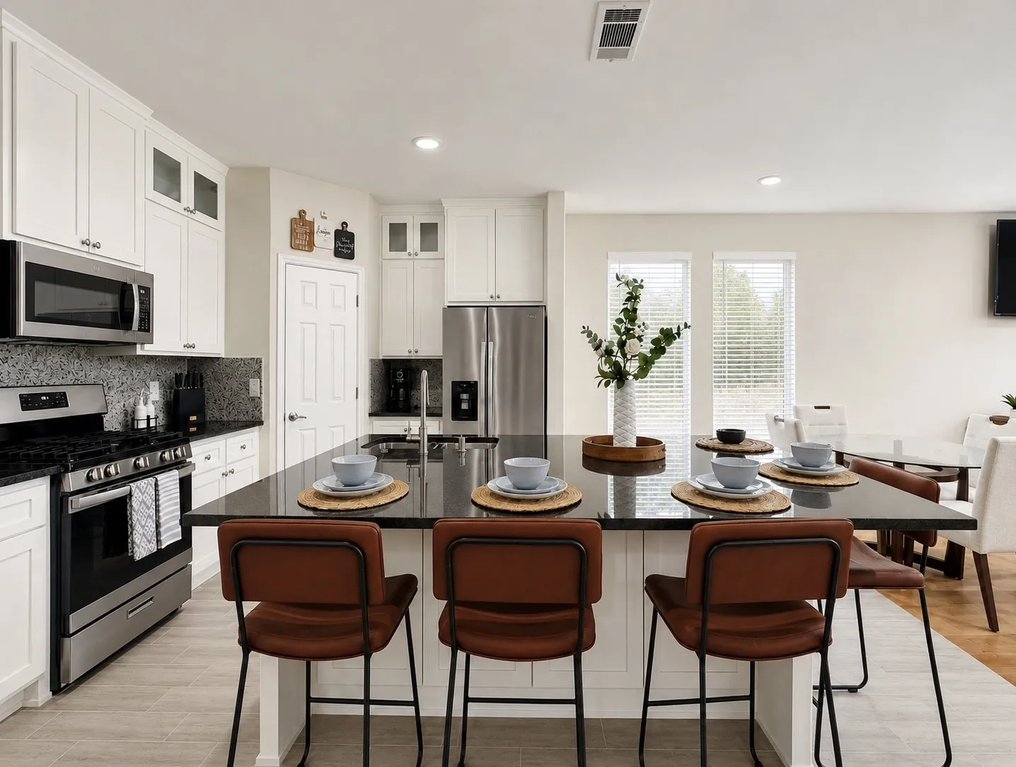 Kitchen featuring a large island with dark stone countertops, white cabinetry, stainless steel appliances, and a tiled backsplash