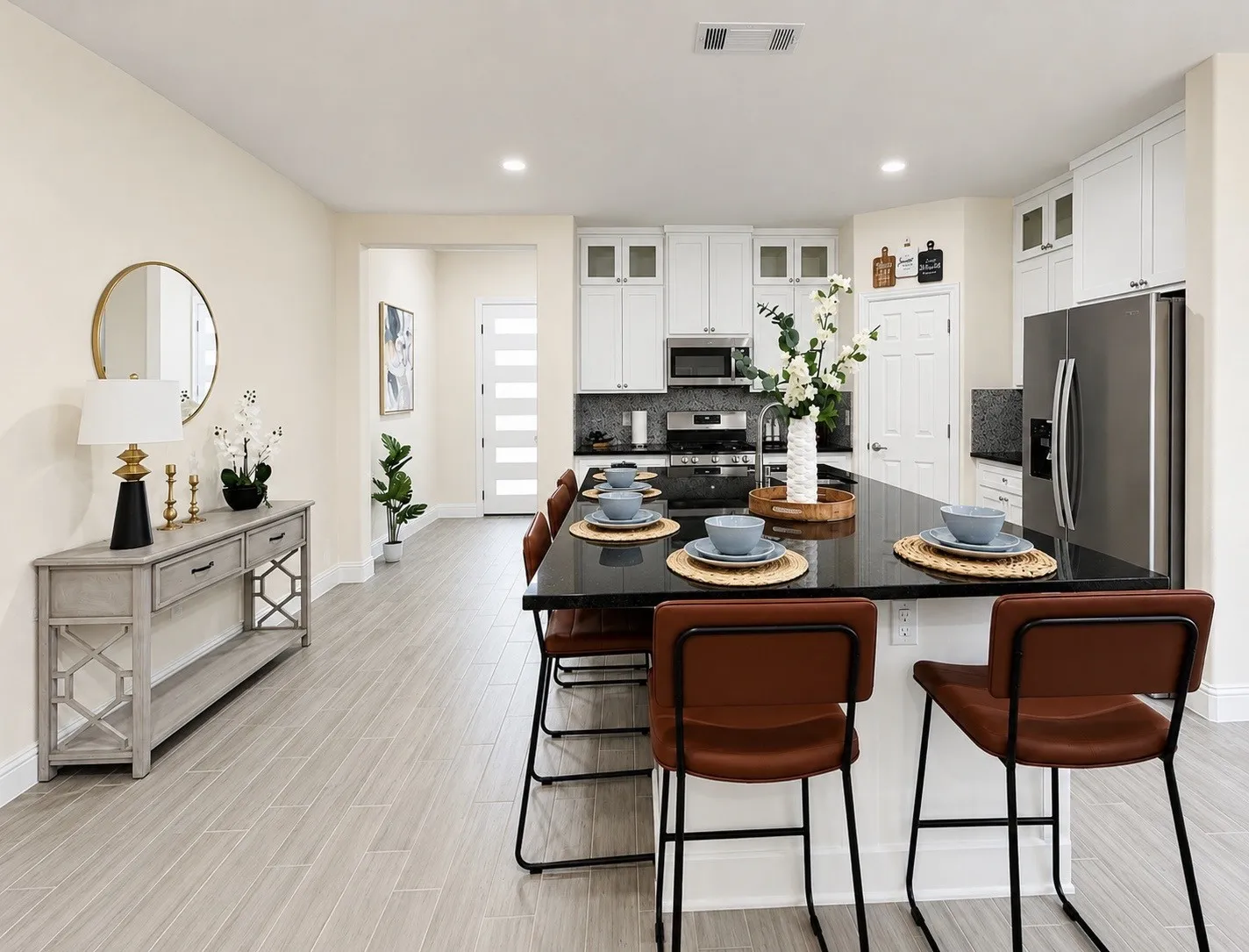 Kitchen featuring a large island with a dark countertop, white cabinetry with glass accents, and stainless steel appliances