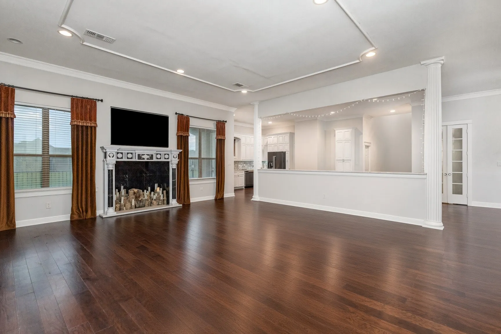 Expansive living space featuring rich wood-finish flooring, a decorative fireplace with an ornate mantel, and a half-wall partition