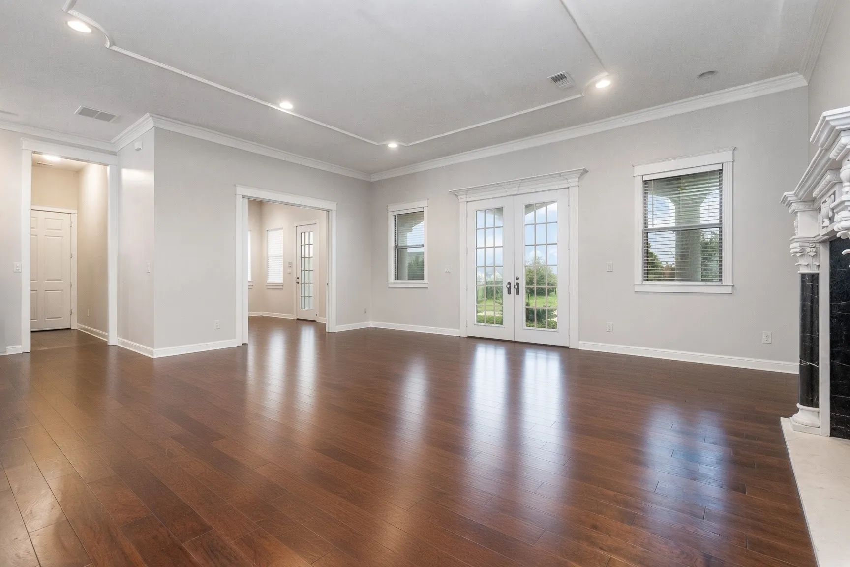 Hardwood flooring, recessed lighting, crown molding, French doors, and a decorative fireplace
