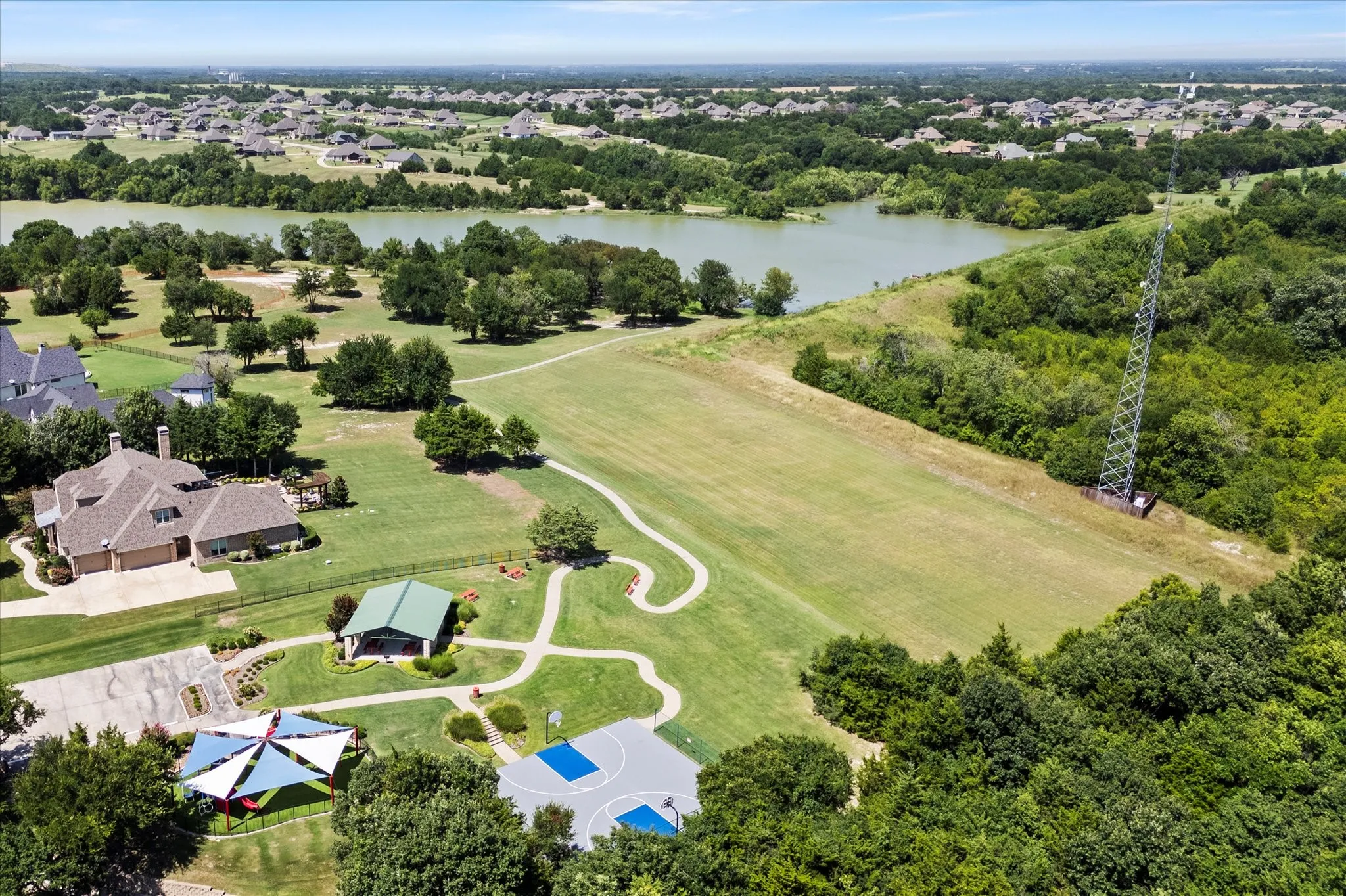 Aerial perspective showcasing a residential area bordered by a body of water and expansive green spaces