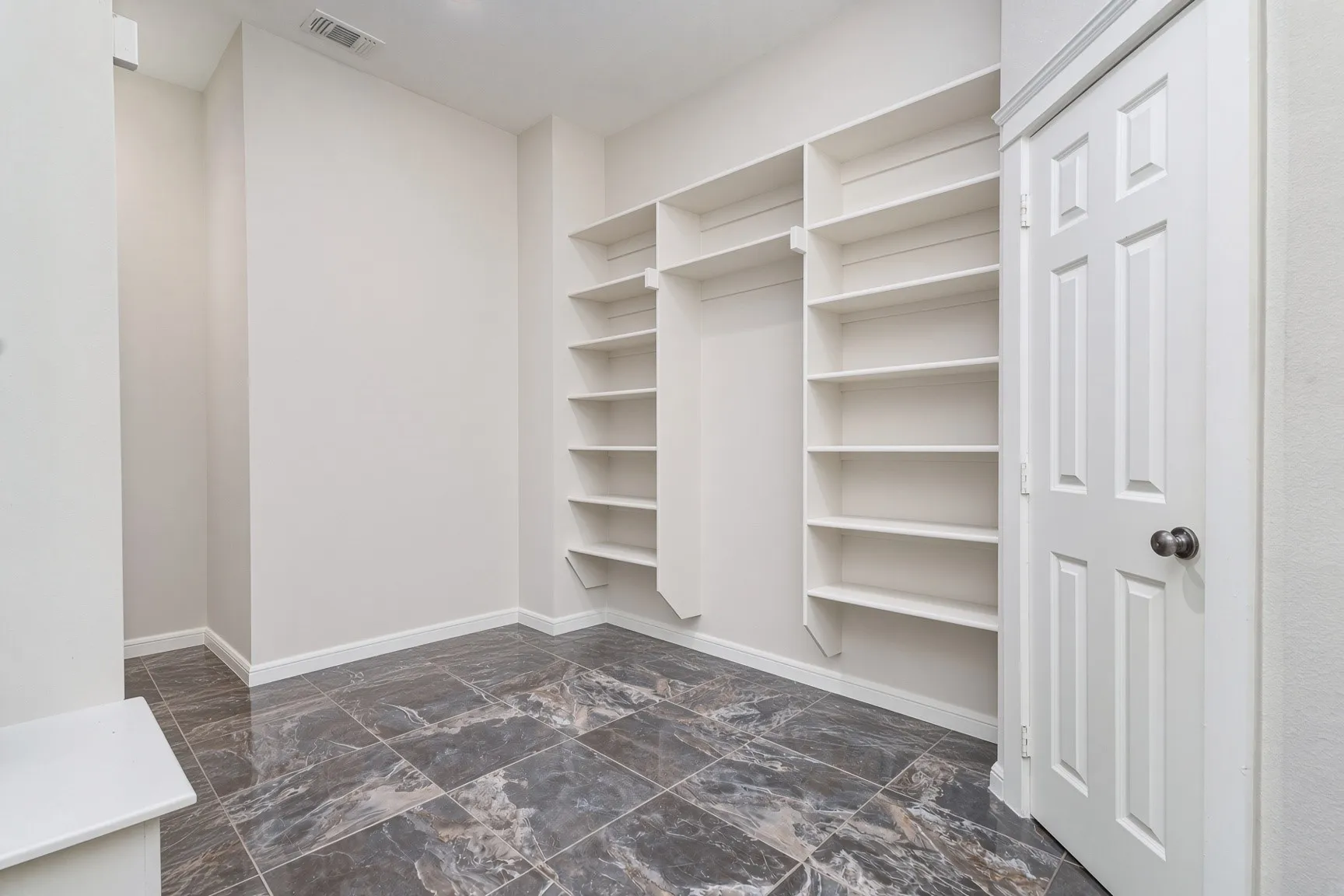 Integrated shelving units, dark-toned tile flooring, and a paneled interior door