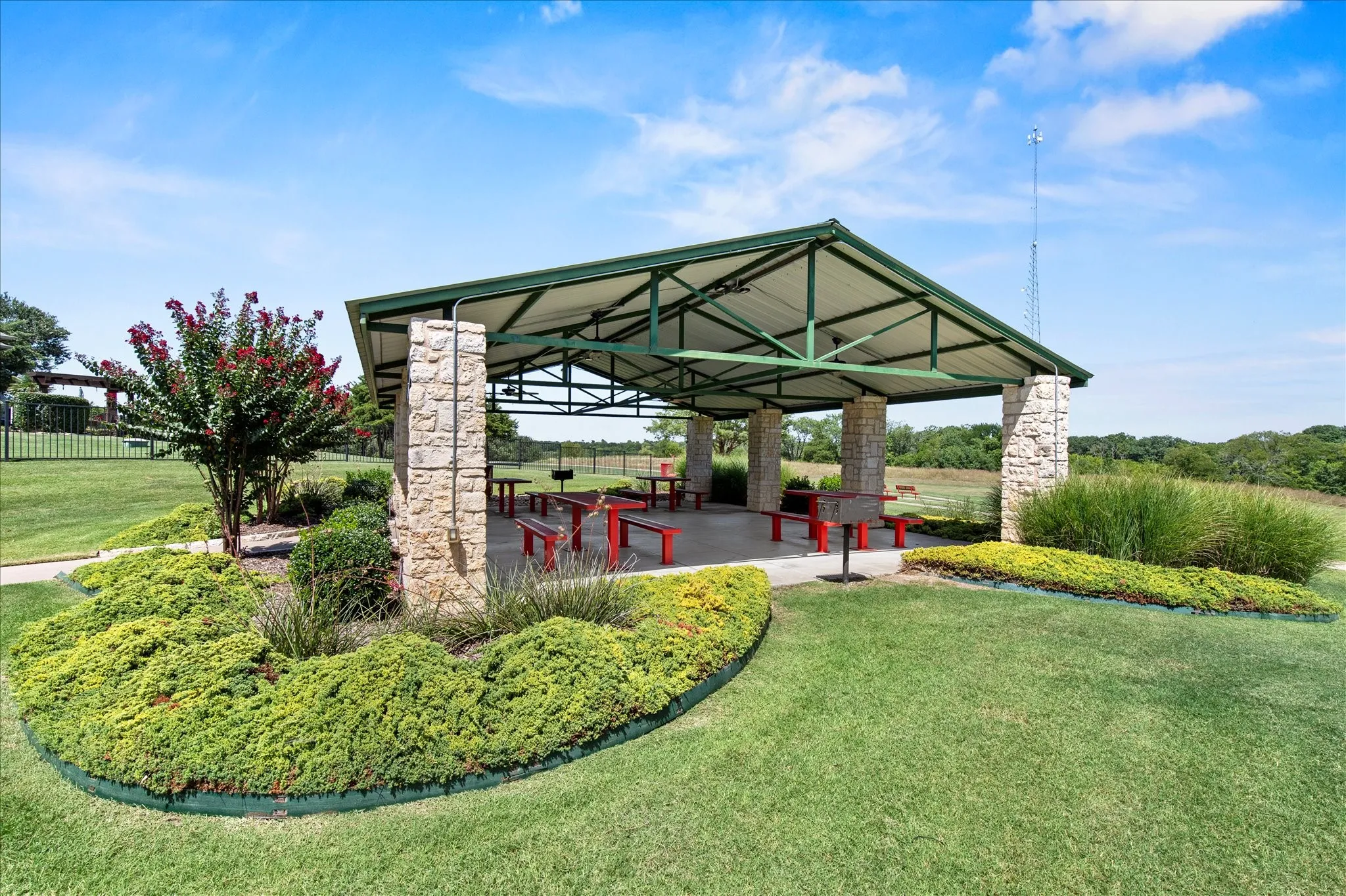 Outdoor pavilion featuring stone pillars supporting a green metal roof