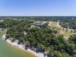 Expansive property with a water frontage, a substantial building, mature trees, and natural landscaping