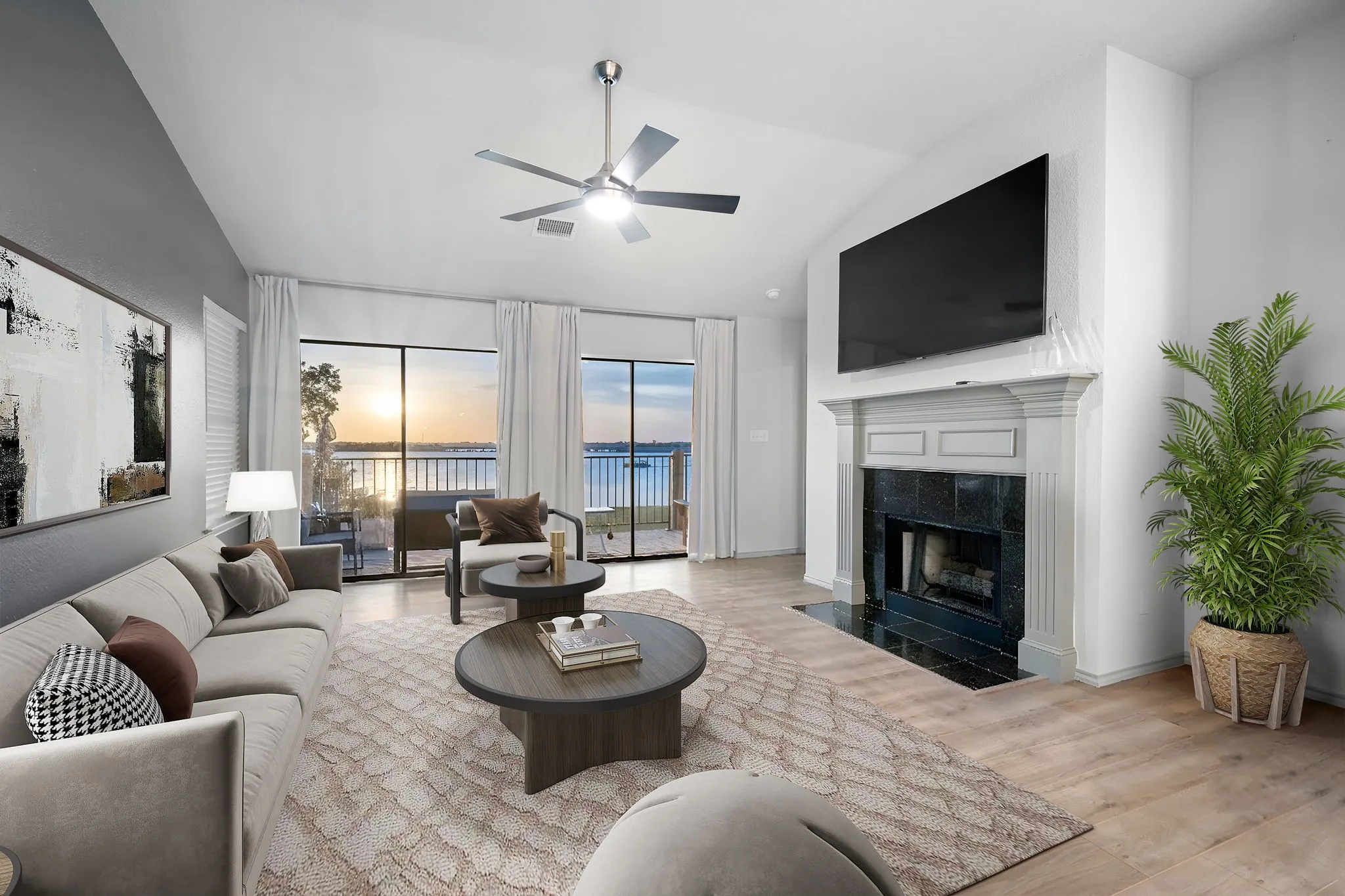 Virtually staged living space with vaulted ceiling and a ceiling fan, featuring large sliding glass doors opening to a balcony