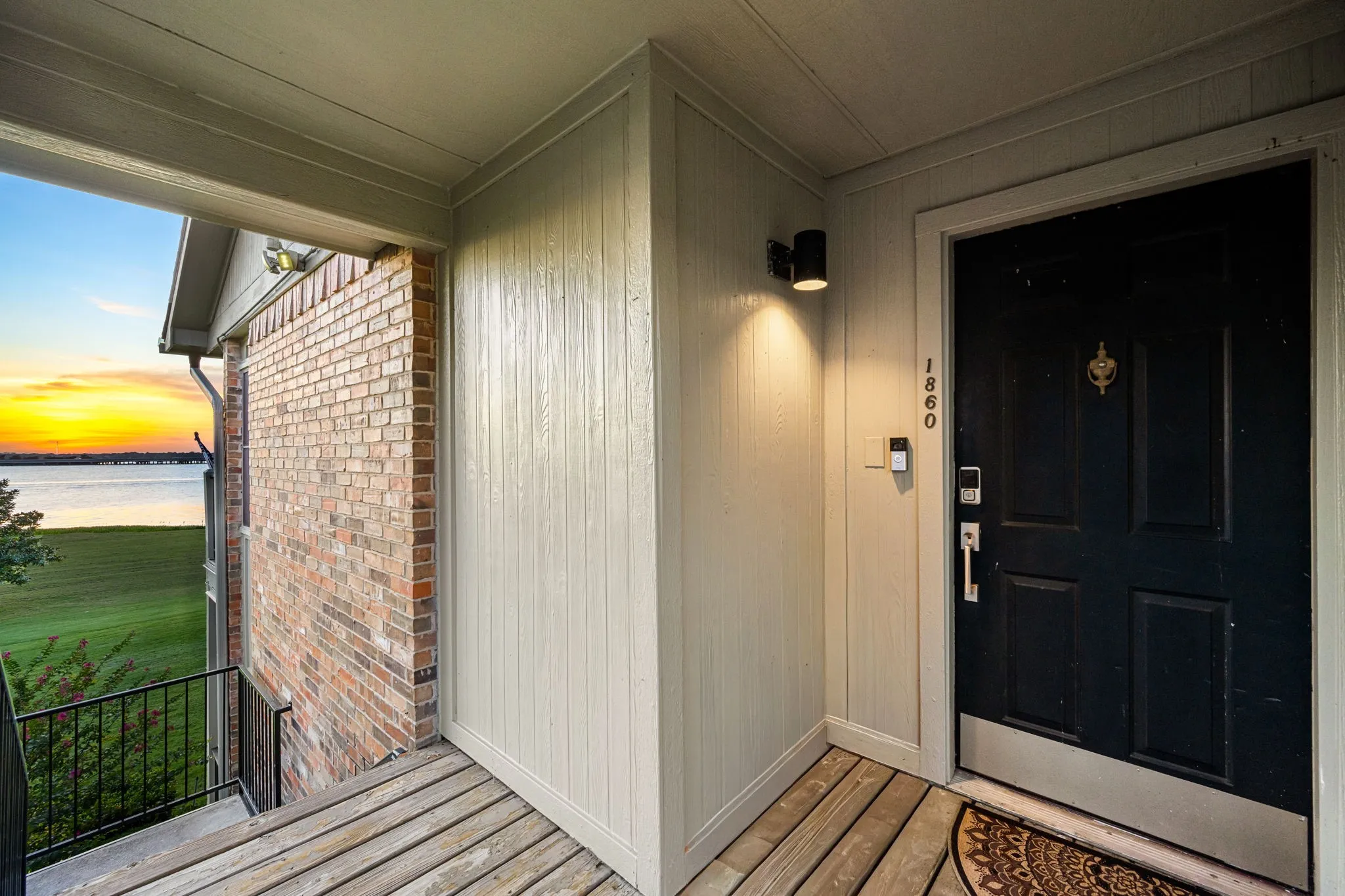 Covered entry featuring wood-finish decking and a dark-paneled door