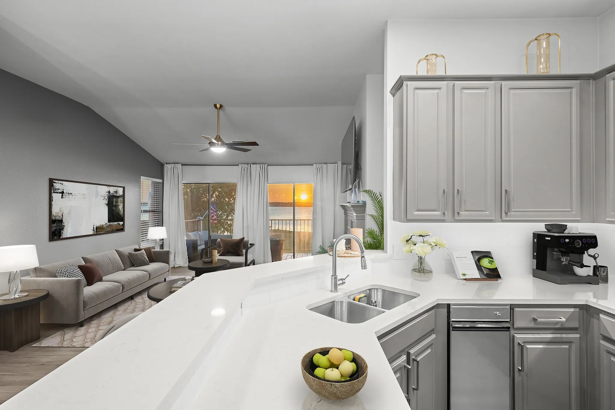 Open-concept kitchen and living area featuring white countertops, stainless steel sink, gray cabinetry, and wood-finish flooring