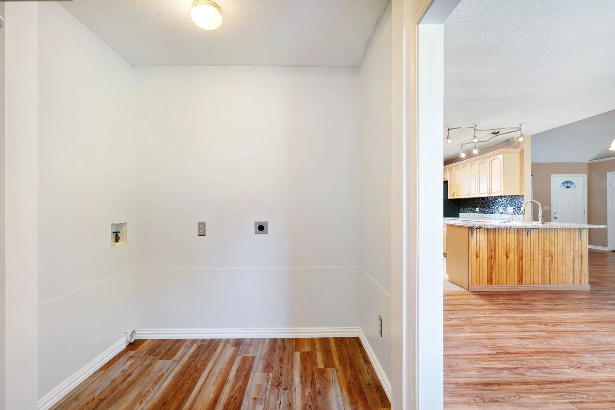 Laundry area with wood-finish flooring, white walls, and a ceiling-mounted light​​‌​​​​‌​​‌‌​‌‌​​​‌‌​‌​‌​‌​​​‌​​ fixture