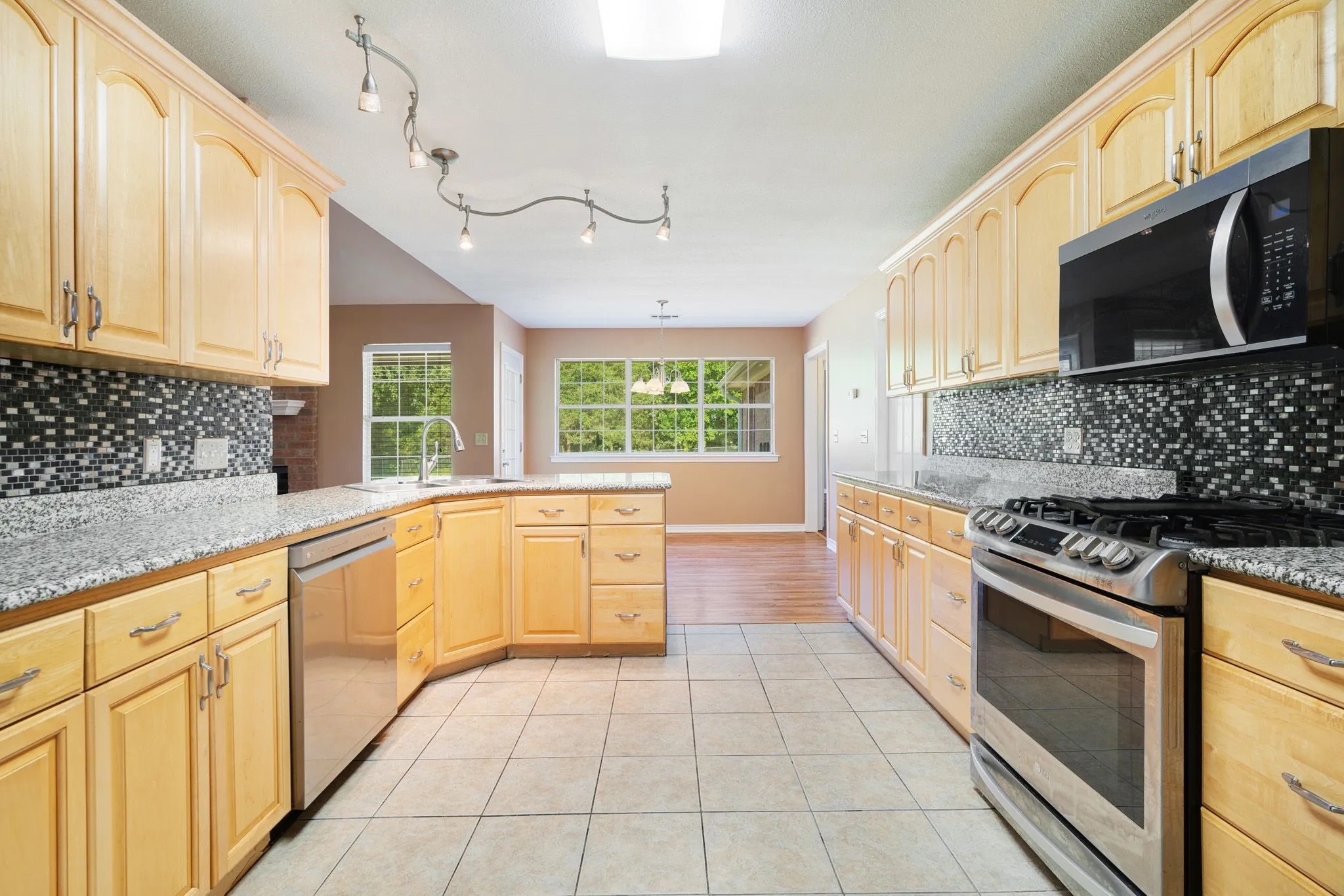 Kitchen featuring wood-finish cabinetry, stainless steel appliances, speckled countertops, and a mosaic tile backsplash