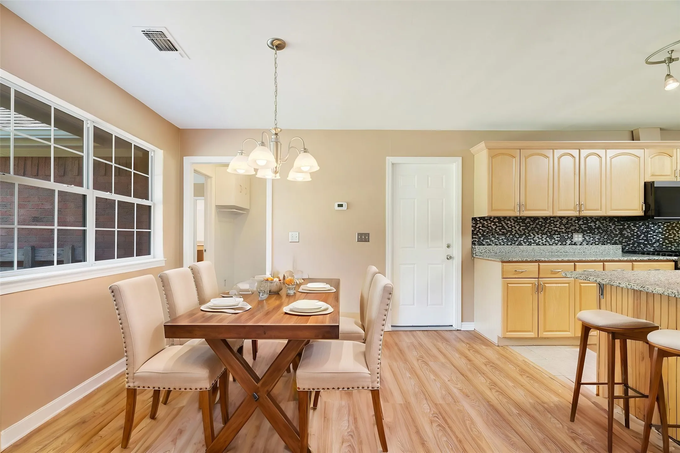 Open-concept dining area featuring wood-finish flooring, a multi-pane window, and a chandelier