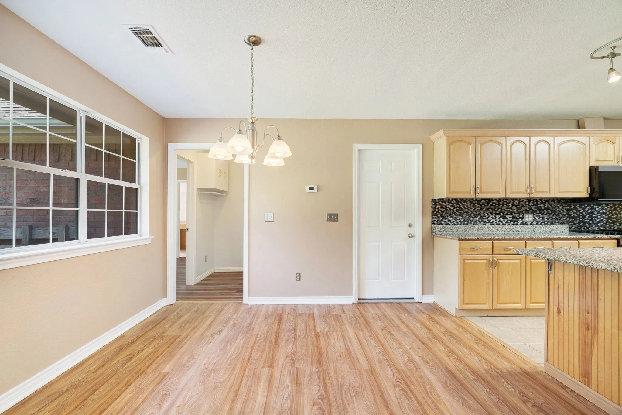 Expansive dining area featuring wood-finish flooring, a multi-pane window, and a chandelier