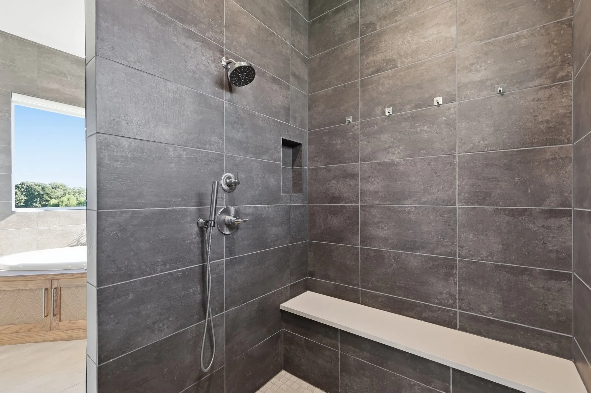 double shower head, sitting bench and shampoo niche intentionally added to be out of sight