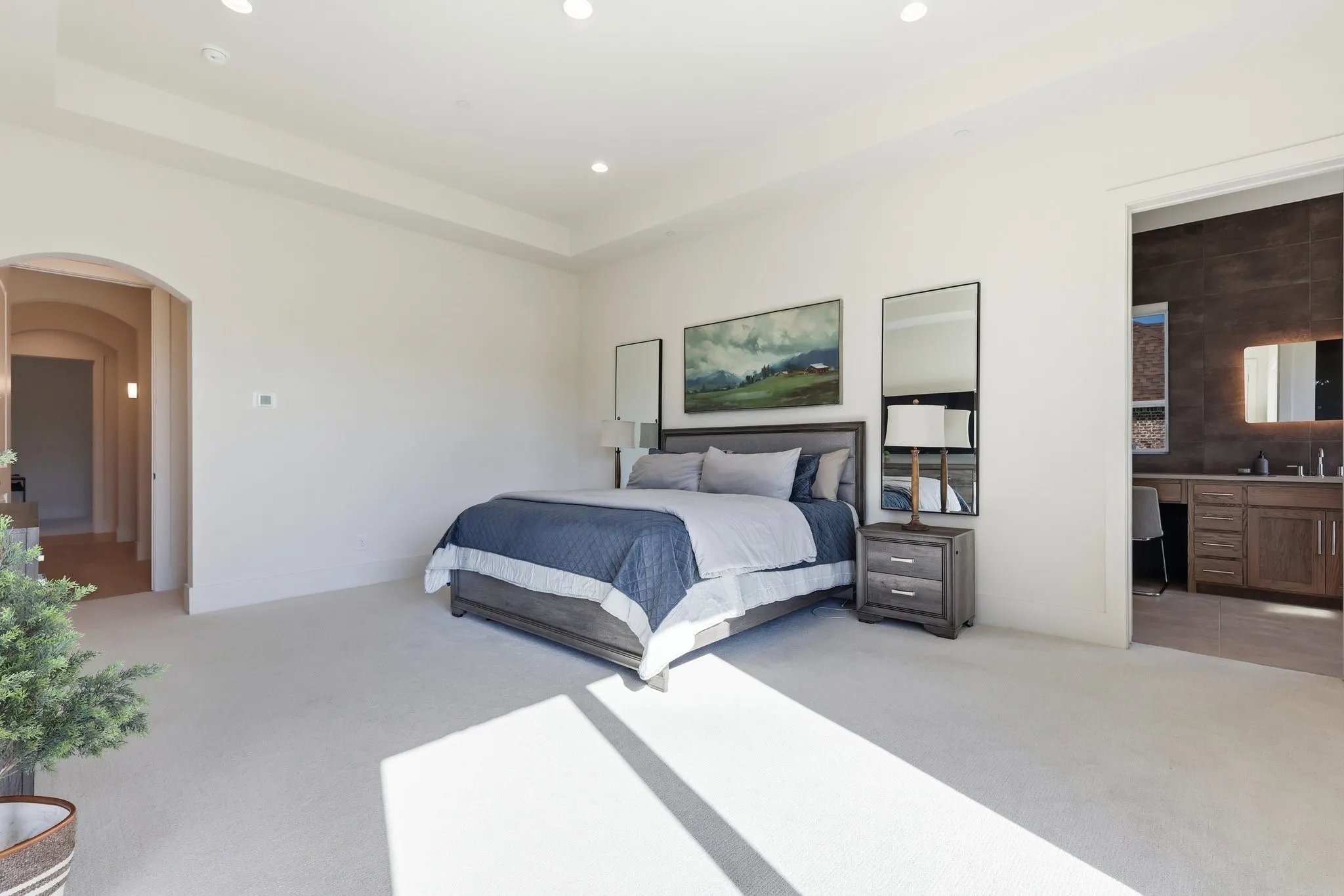 Primary bedroom at the end of arched hallway with custom wall sconces.